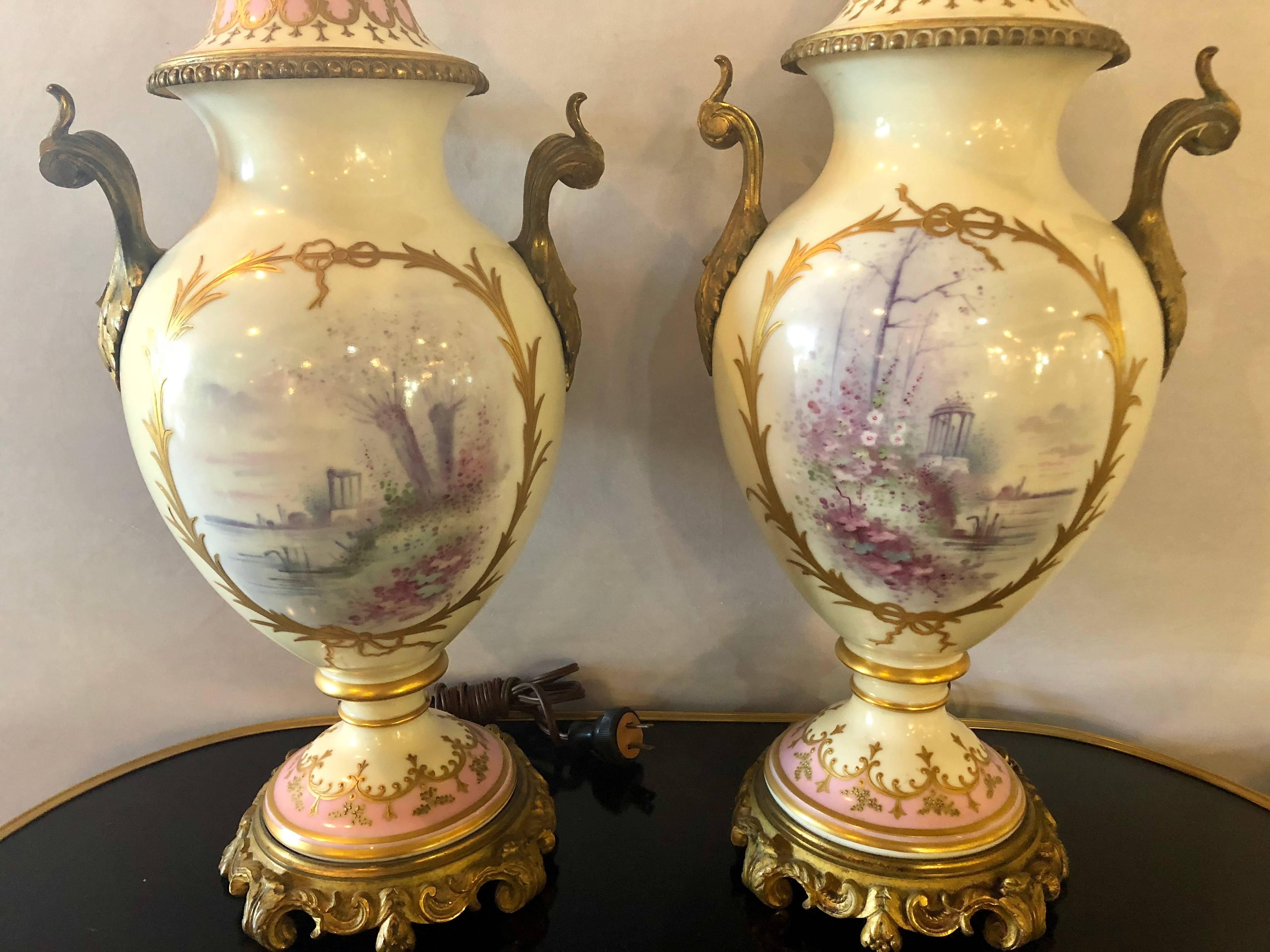 Pair of late 19th-early 20th century. bronze-mounted French Porcelain Lidded Urns, wired as table lamps, artist signed 'R. Pierens' painted and gilt decoration depicting women with cherubs and garden landscapes, stamped with Sevres blue mark of