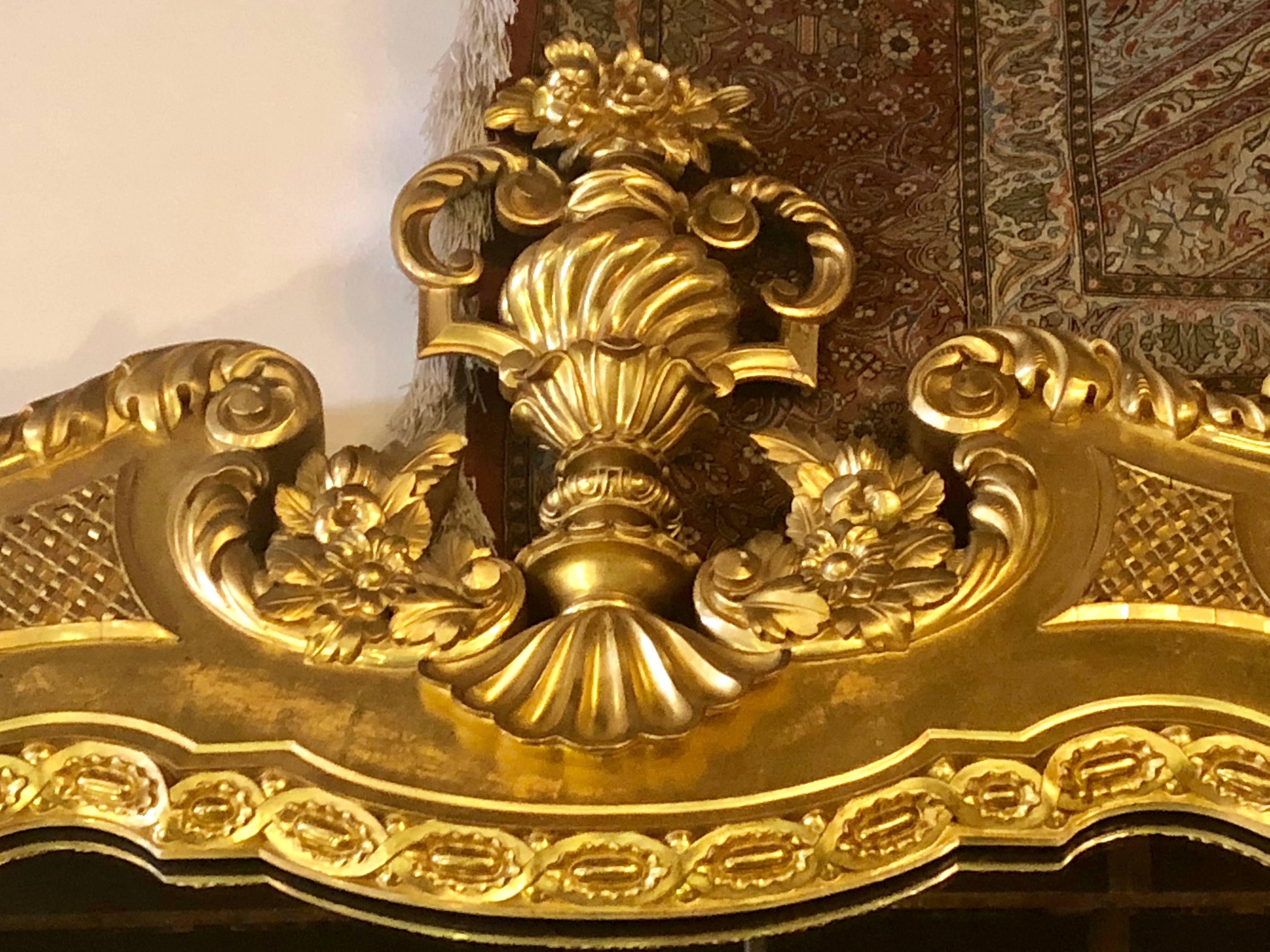 Monumental pair of finely carved 84 x 53 inch Italian console or wall mirrors with flame and floral finial tops. This finely giltwood pair of mirrors have clay undertones and are not only impressive in size but quality as well. Certainly having been
