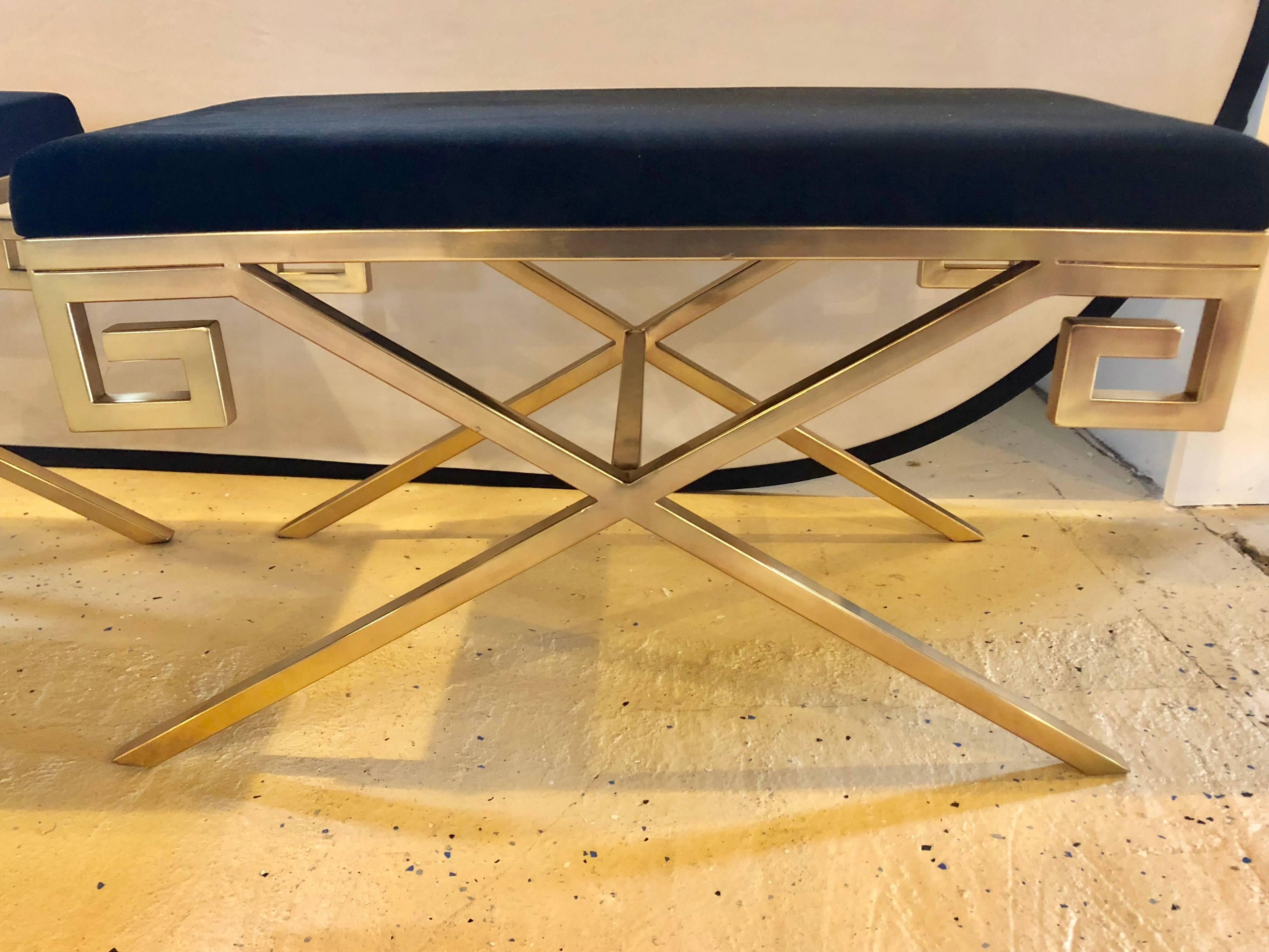 Pair of gold tone metal and black contemporary upholstered benches or footstools. Each having a metal base of X and form with Greek key design.