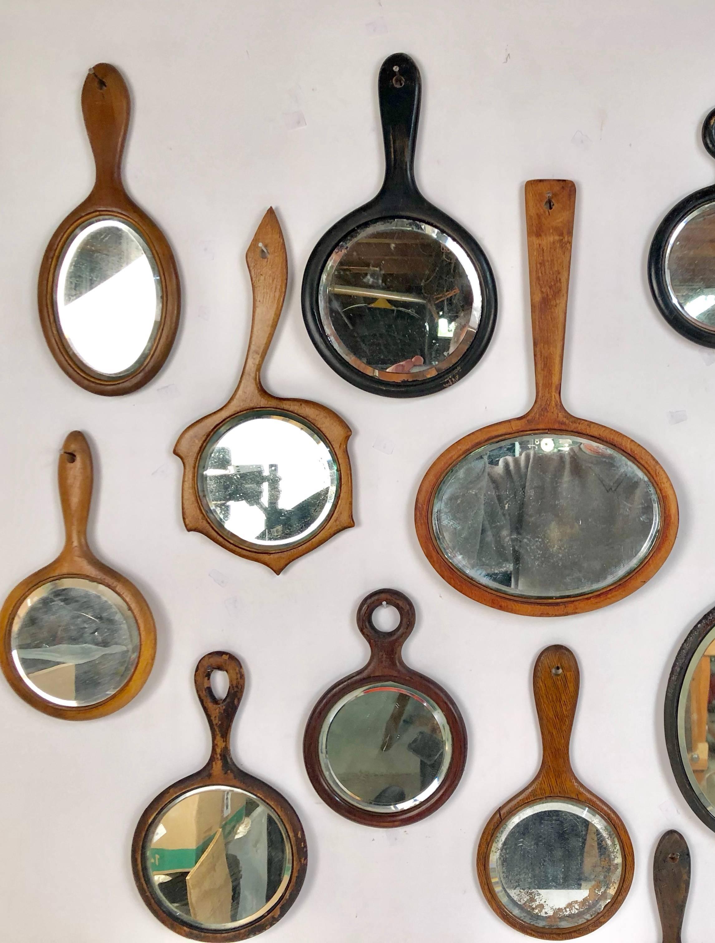 Collection of 18 antique wooden handle bevelled glass hand mirrors. Some very unusual and rare shapes. The largest measures 14 x 9.75 x .38. The smallest 4.5 x 2.5 x .13.