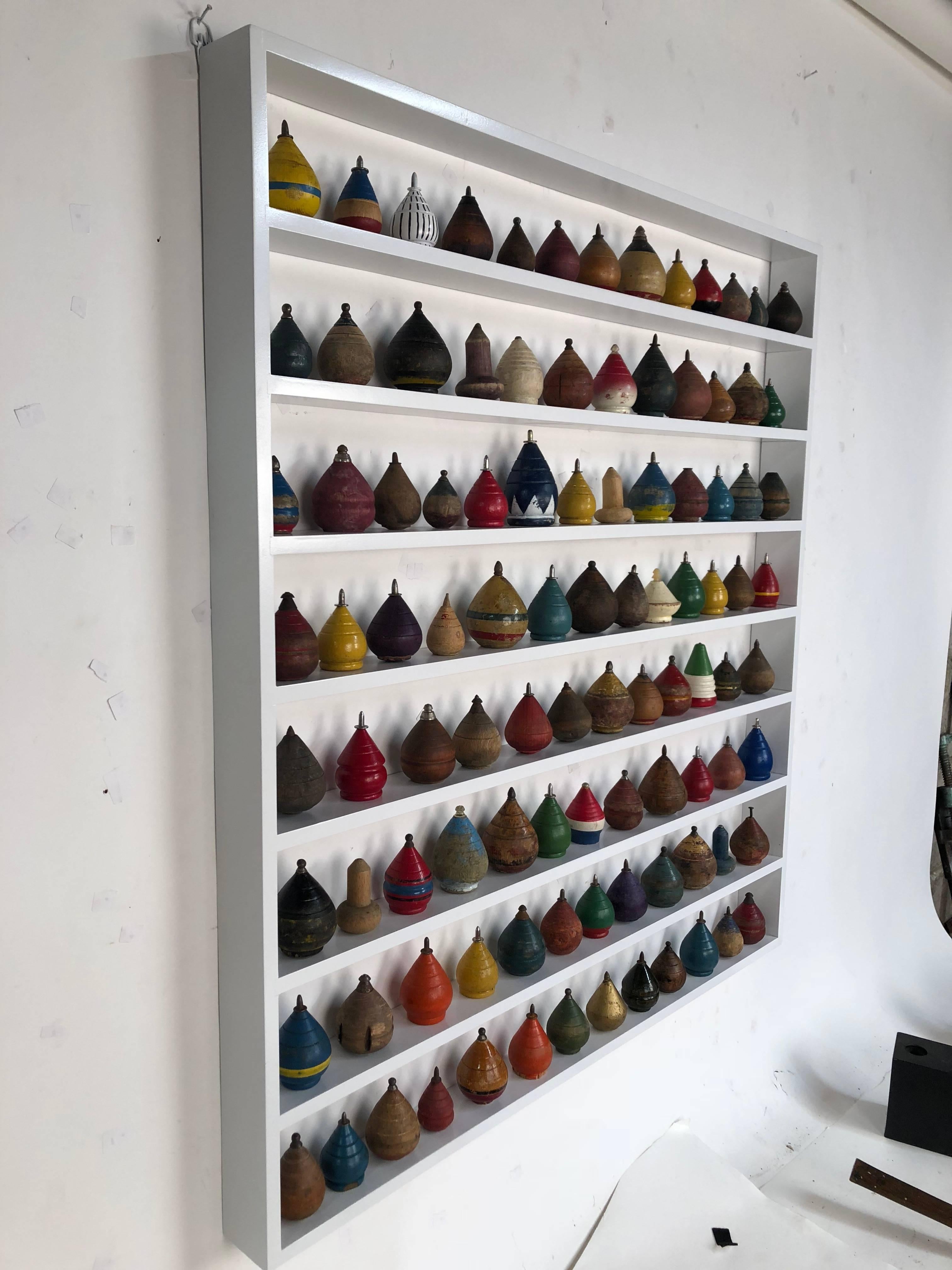 Collection of 100 antique spinning tops in a custom shadow box frame.