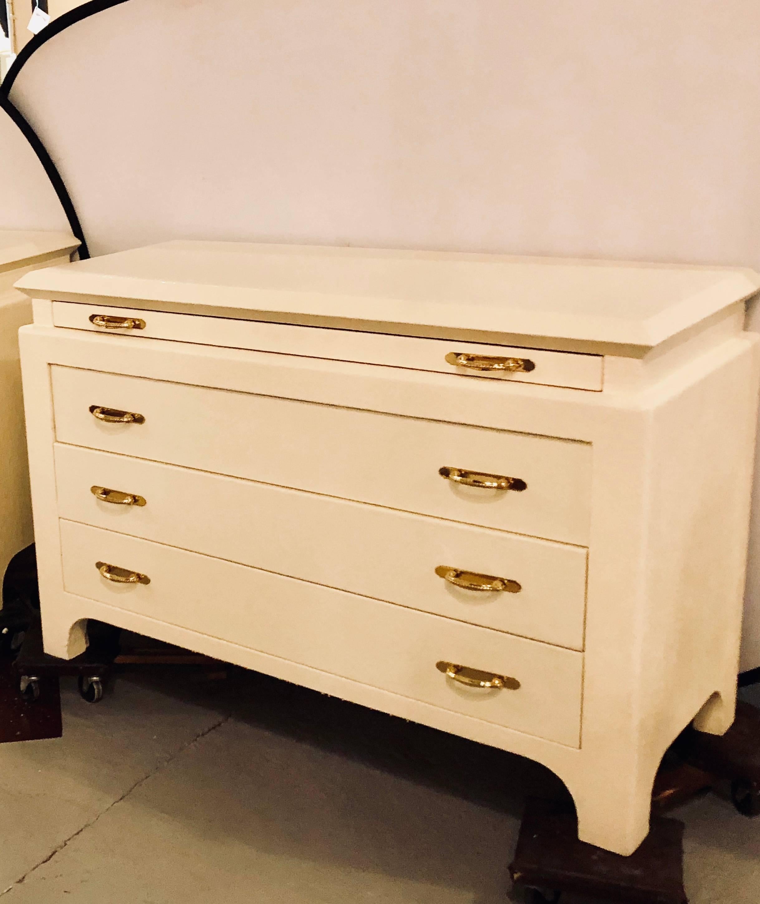 A pair of custom quality commodes, chests or nightstands each linen wrapped. The pair having oak lined interiors of three drawers with bronze pulls under a large pull-out tray all of which slide and glide effortlessly. The whole sitting on bracket.