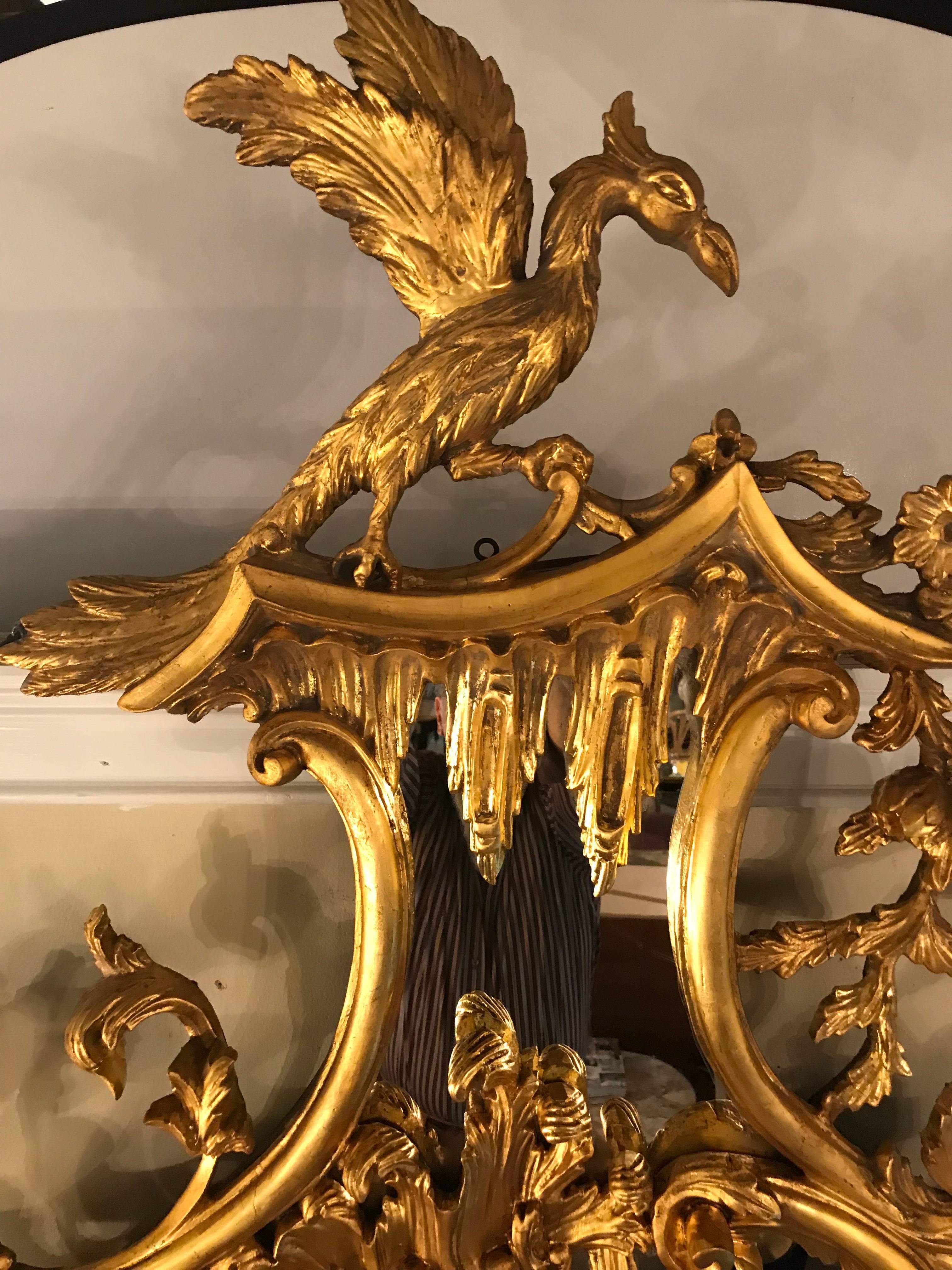 A pair of Palatial George II style giltwood wall or console mirrors. Each mirror set in a wood frame that is gilt gold decorated. Both having wonderful pediment tops depicting winged phoenix's along with foliate leaf and vine decorations. The centre