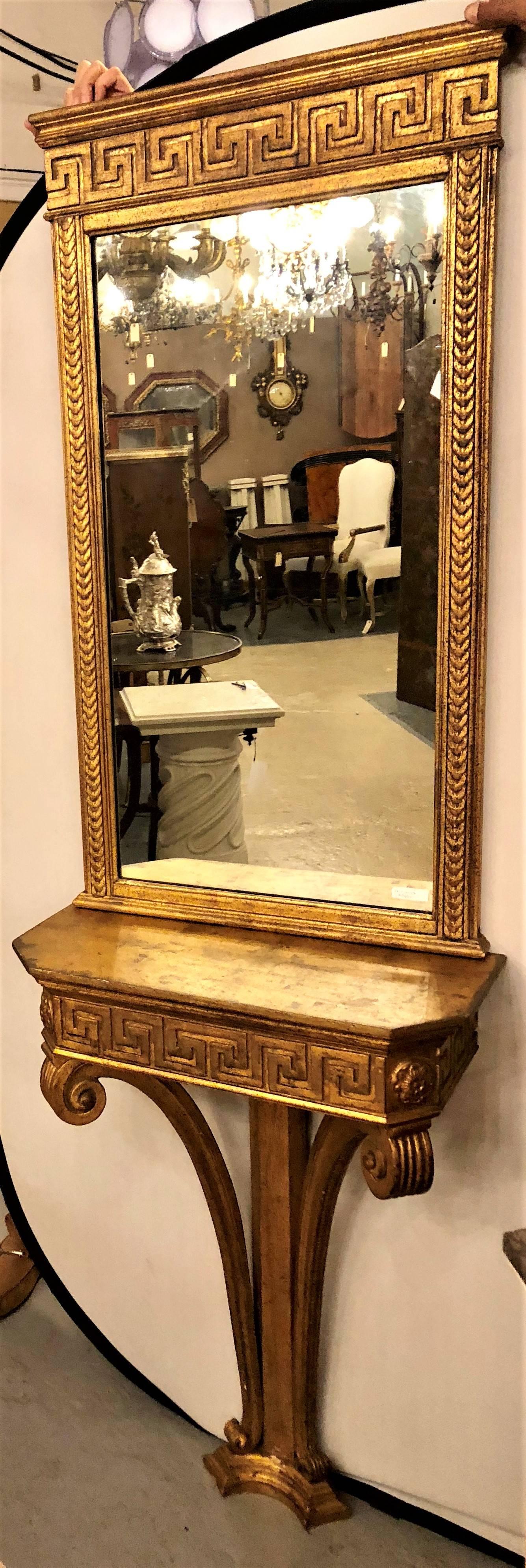 A fine Italian Greek key designed console table with matching wall mirror. Both of gilt gold design with plume decorated legs. This classically designed console and matching wall mirror are sure to sparkle in any Hollywood Regency style