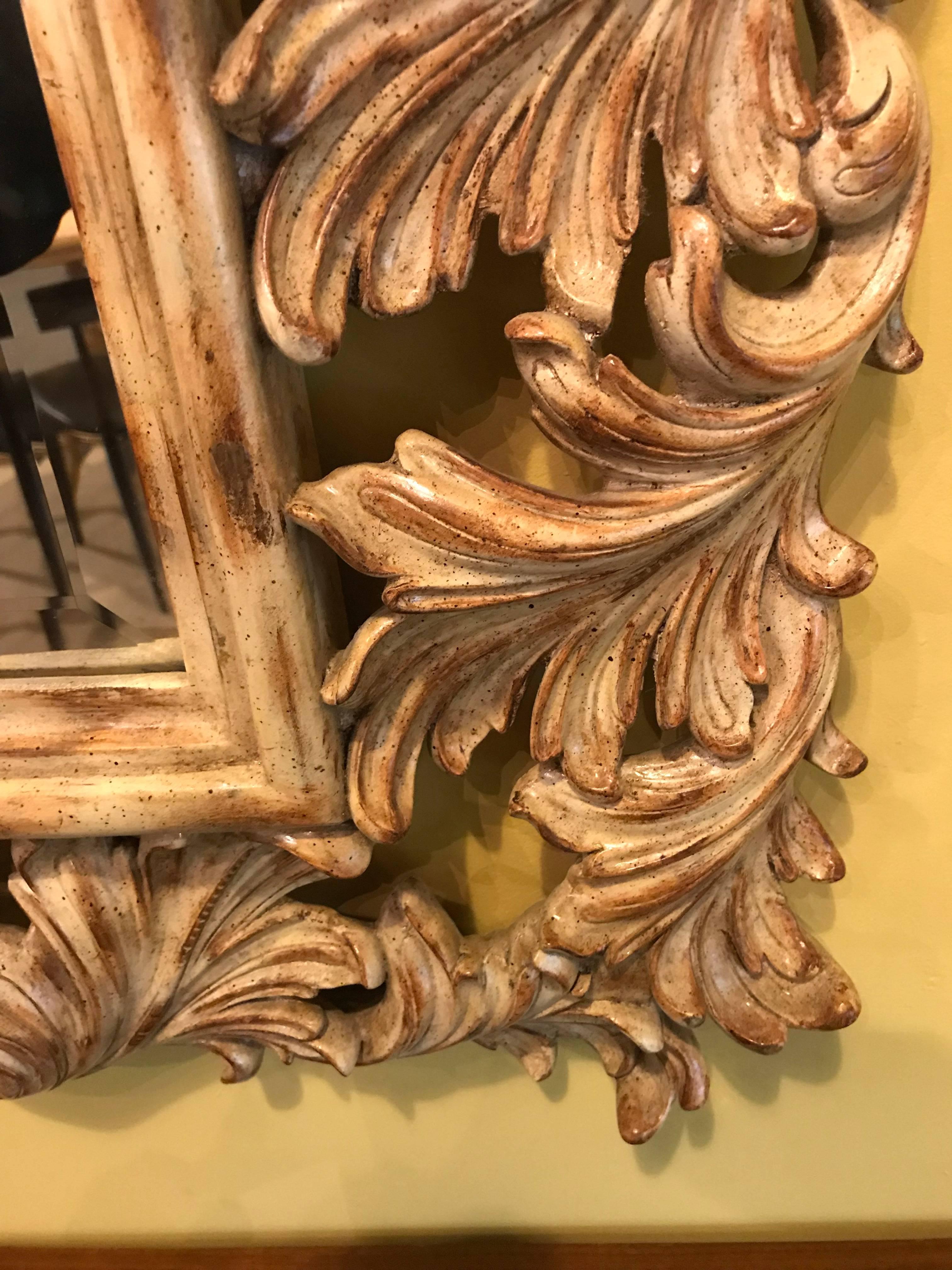 Heavily carved French or Italian frame flanking a bevelled glass wall or console mirror. The frame designed with mostly leave carvings of wood flanking a bevelled mirror.