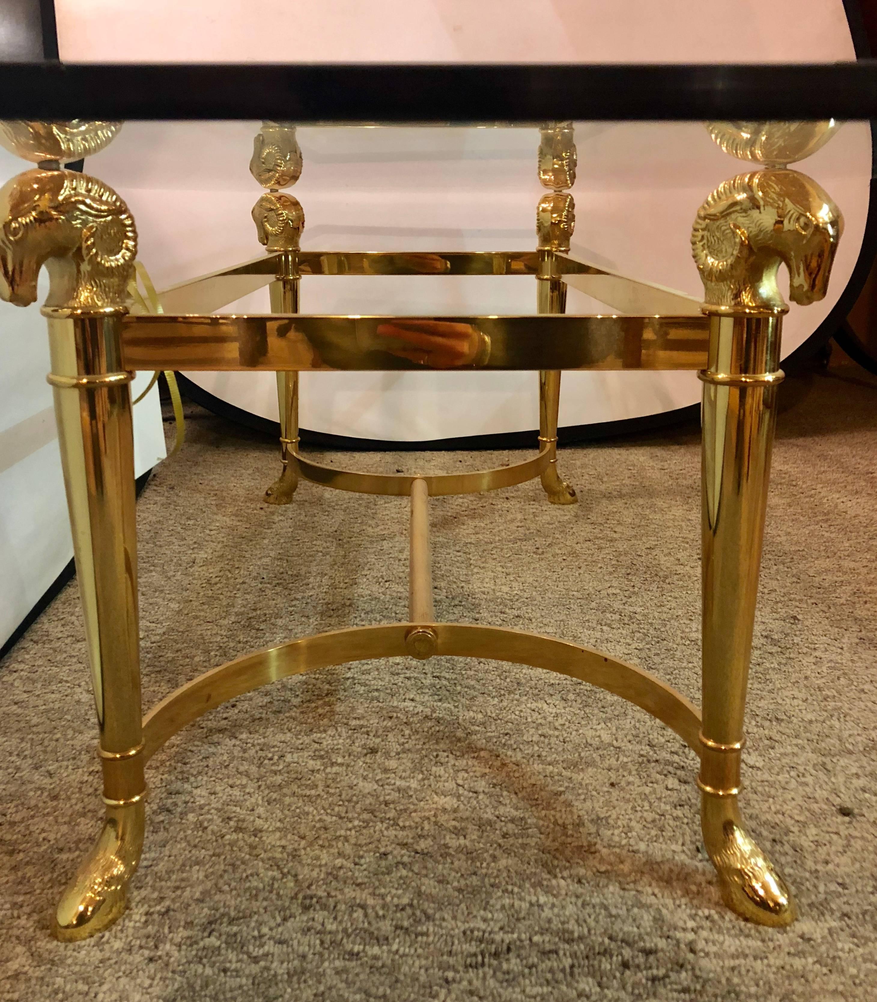 Jansen fashioned octagon bevelled glass top coffee table having heavy brass ram head tops and claw feet.