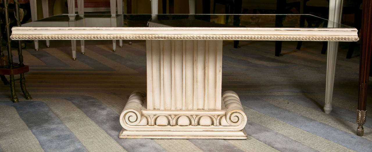 An off-white paint decorated coffee - low table by Grosfeld House. The pilaster column base supporting a wooden gallery mirrored top.