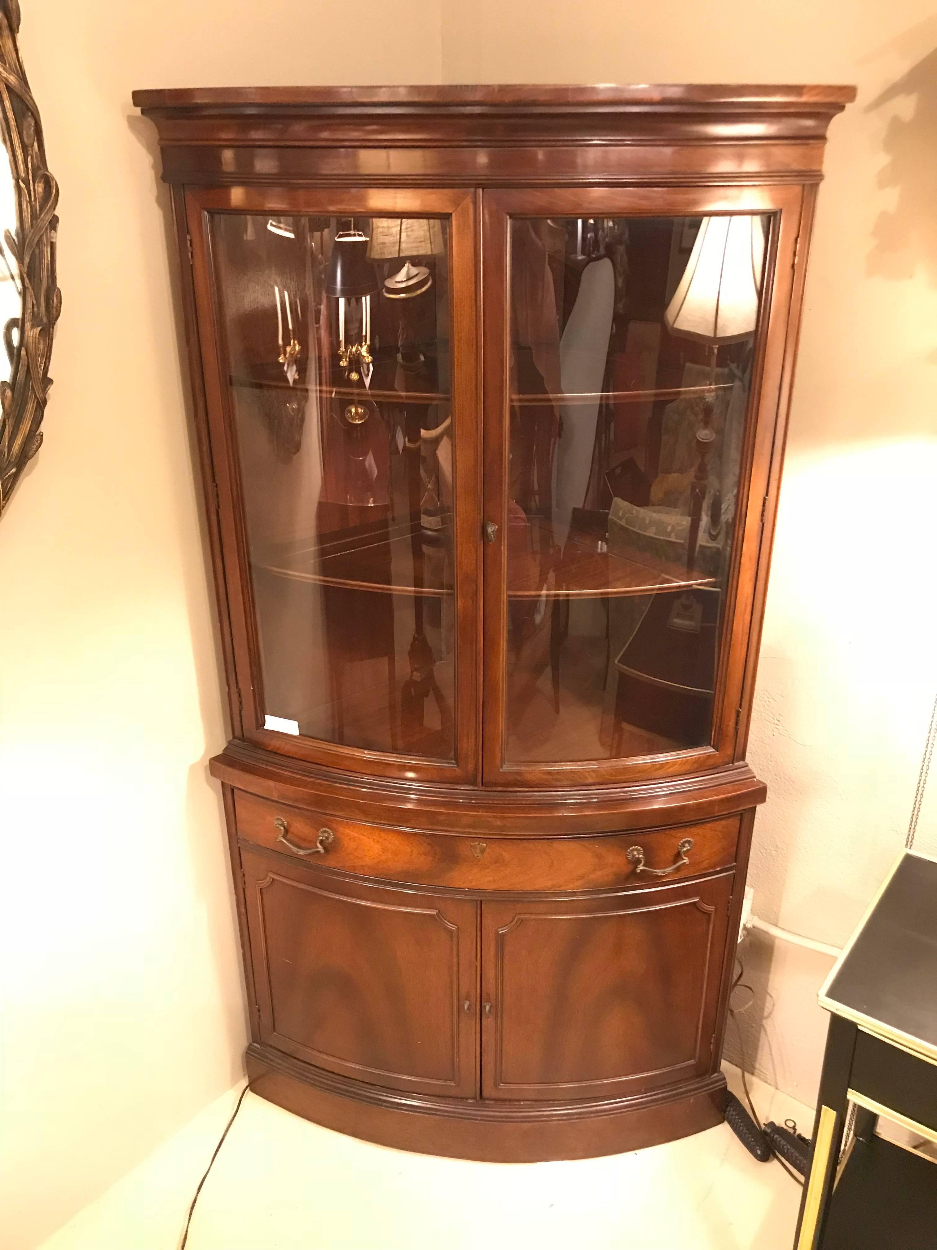 Pair of Georgian style flame mahogany two-door bow front corner cabinets. Each of these fine custom quality corner cabinets hide wonderfully and take up very little room as they sit snugly in any corner of the home or dining area. The bow front
