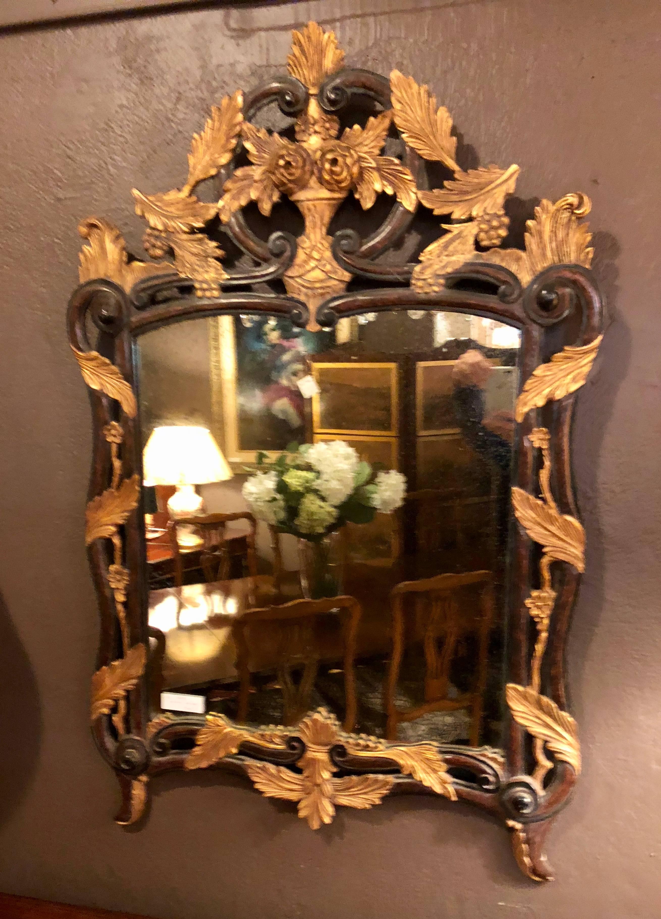French Regency antique mirror of mahogany and gilt with basket of roses design. The gilt on this piece is exceptional as are the carvings of grapes, roses, vines and scrolls that flanked the antique centre mirror.
