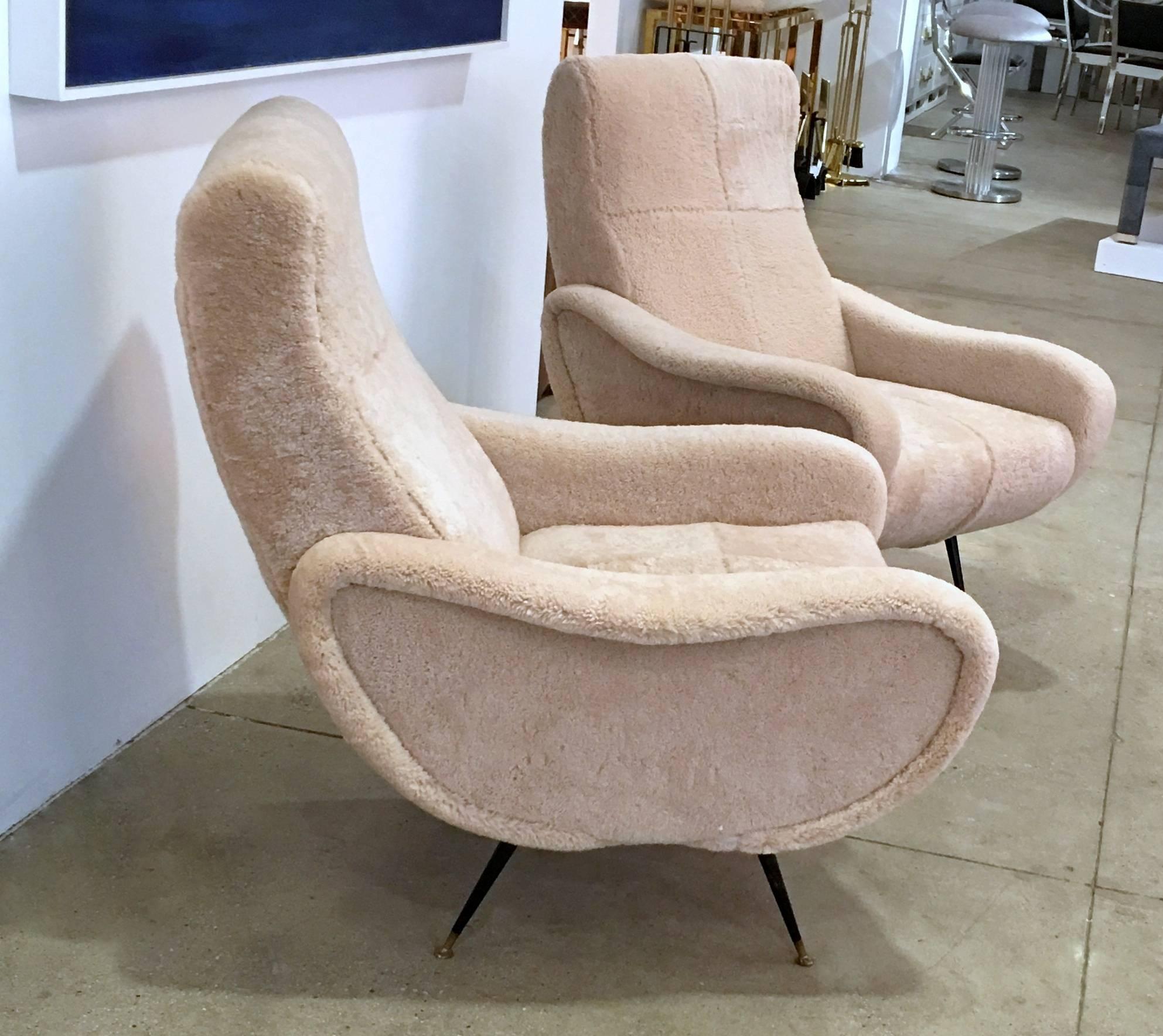 Pair of Mid-Century Italian chairs recently upholstered in shearling with black metal legs and brass feet.