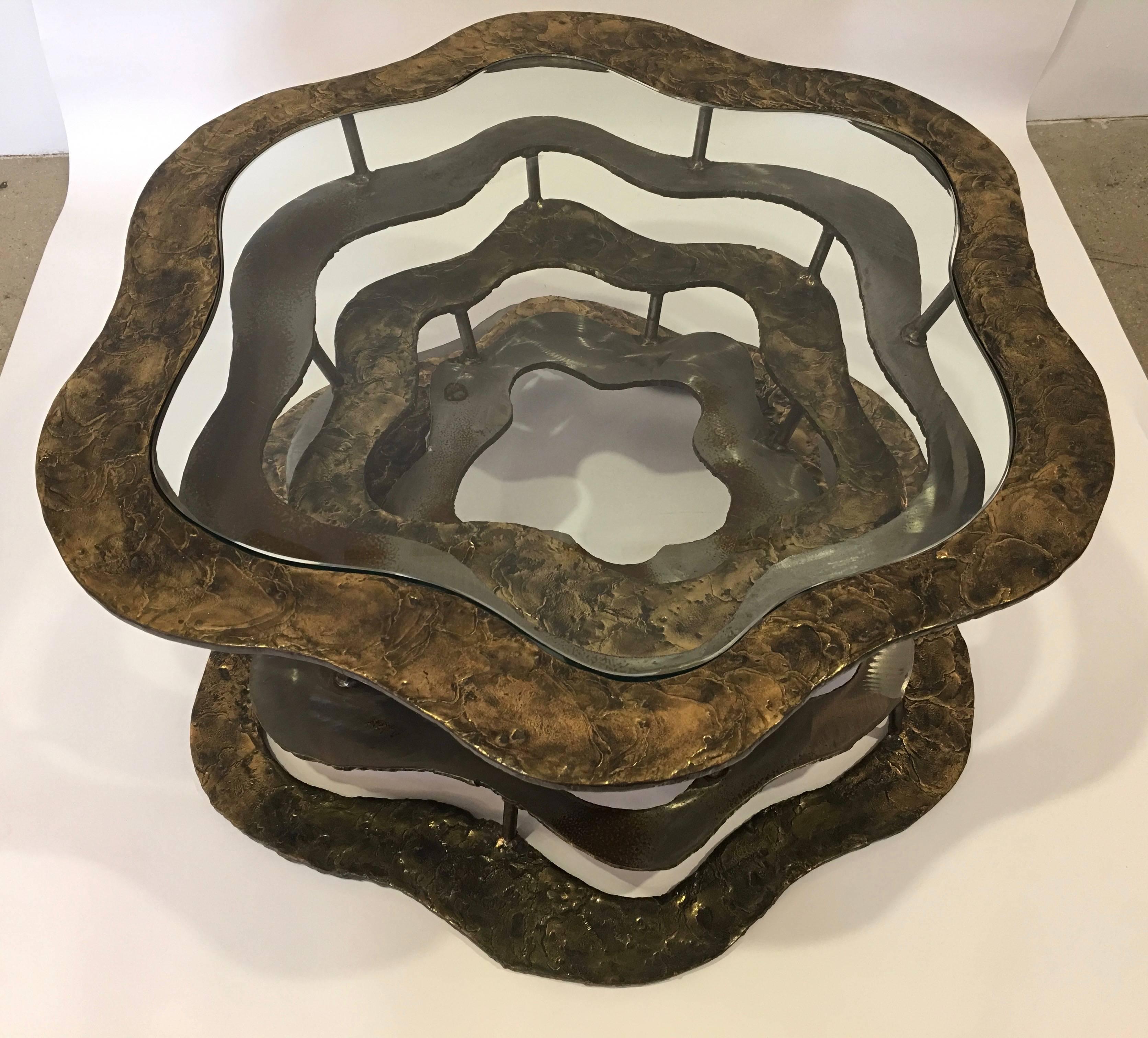 Contemporary New York sculptor Silas Seandel's Volcano coffee table with glass top was made in 1977. The table consists of 7 alternating textured bronze and matte finished stainless steel amorphic rings. Each ring above the base has a series of