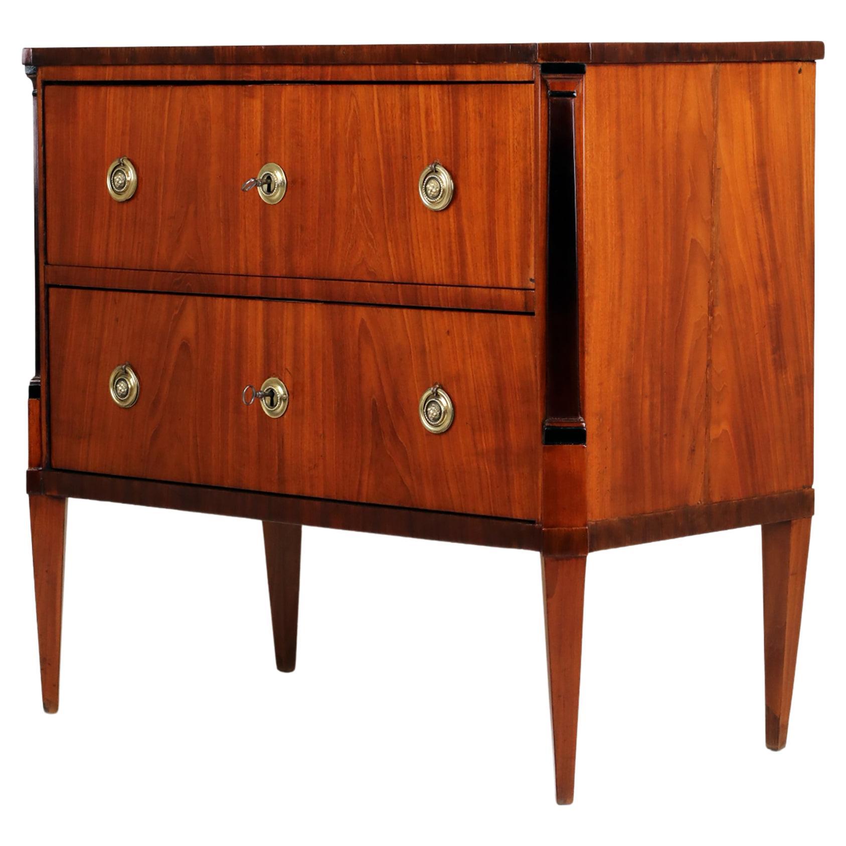 Early 19th Century Chest of Drawers
Germany, 1800
Mahogany 

Elegant Chest with two drawers standing on pointed feet. The front of the chest symmetrically veneered. Edge of the base and edge of the top with a subtly darker contrast. Ebonised