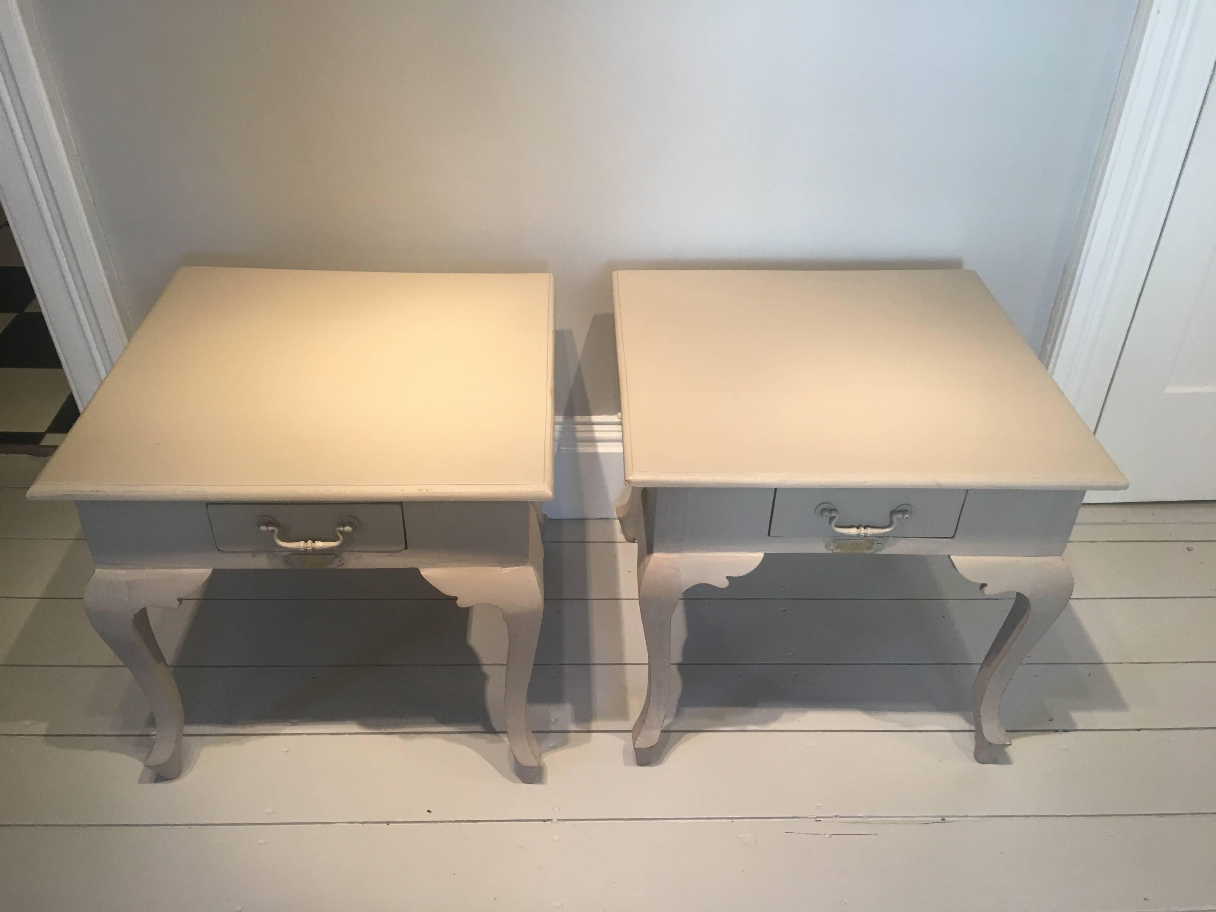 This classically-styled pair of painted side tables is signed 