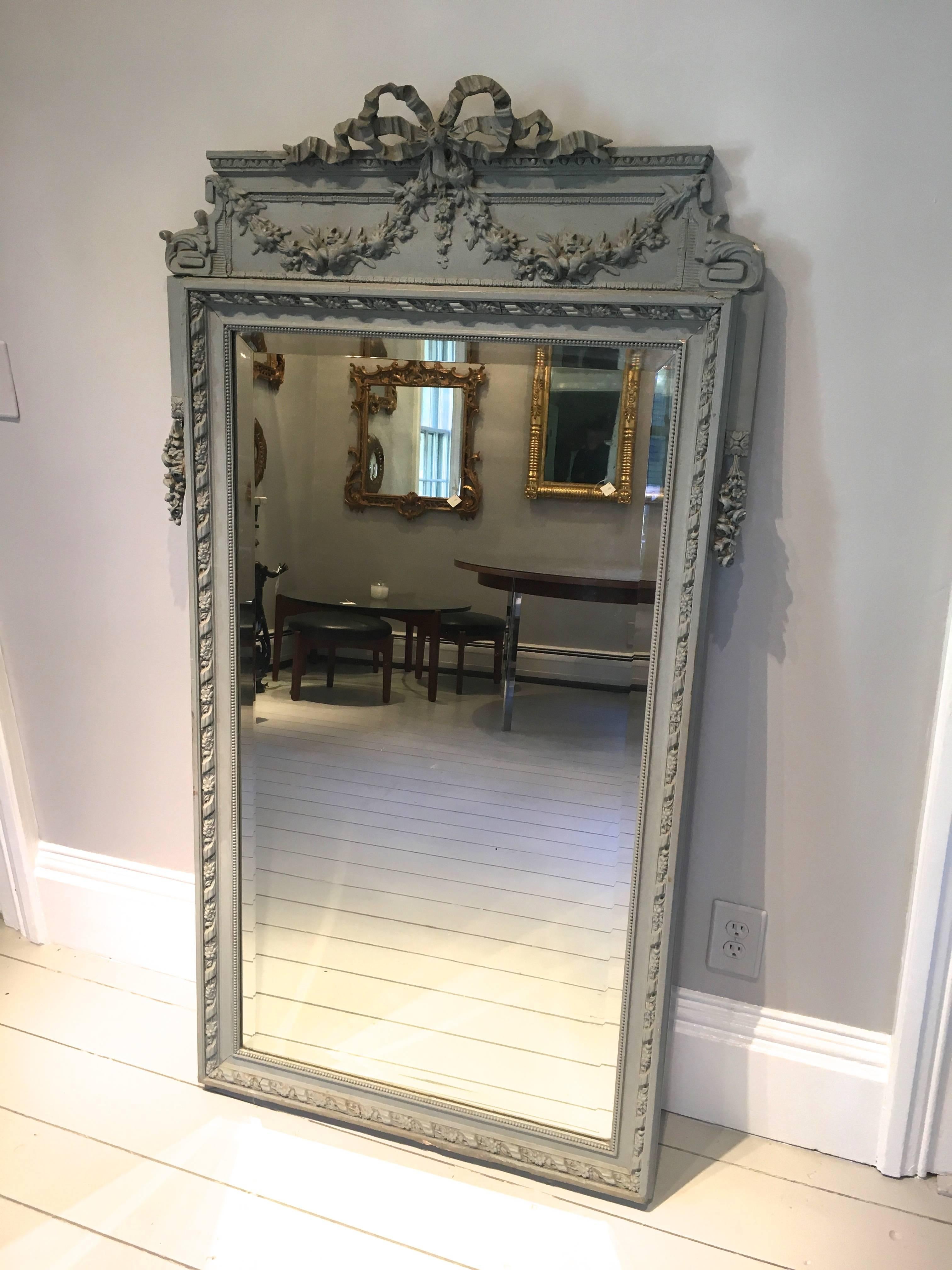 This Classic Beaux Arts French mirror is traditionally made from painted wood and gesso and features its original beveled mirror. There is a small amount of cracking to the paint and a few dings to the gesso, but overall, the mirror is in great