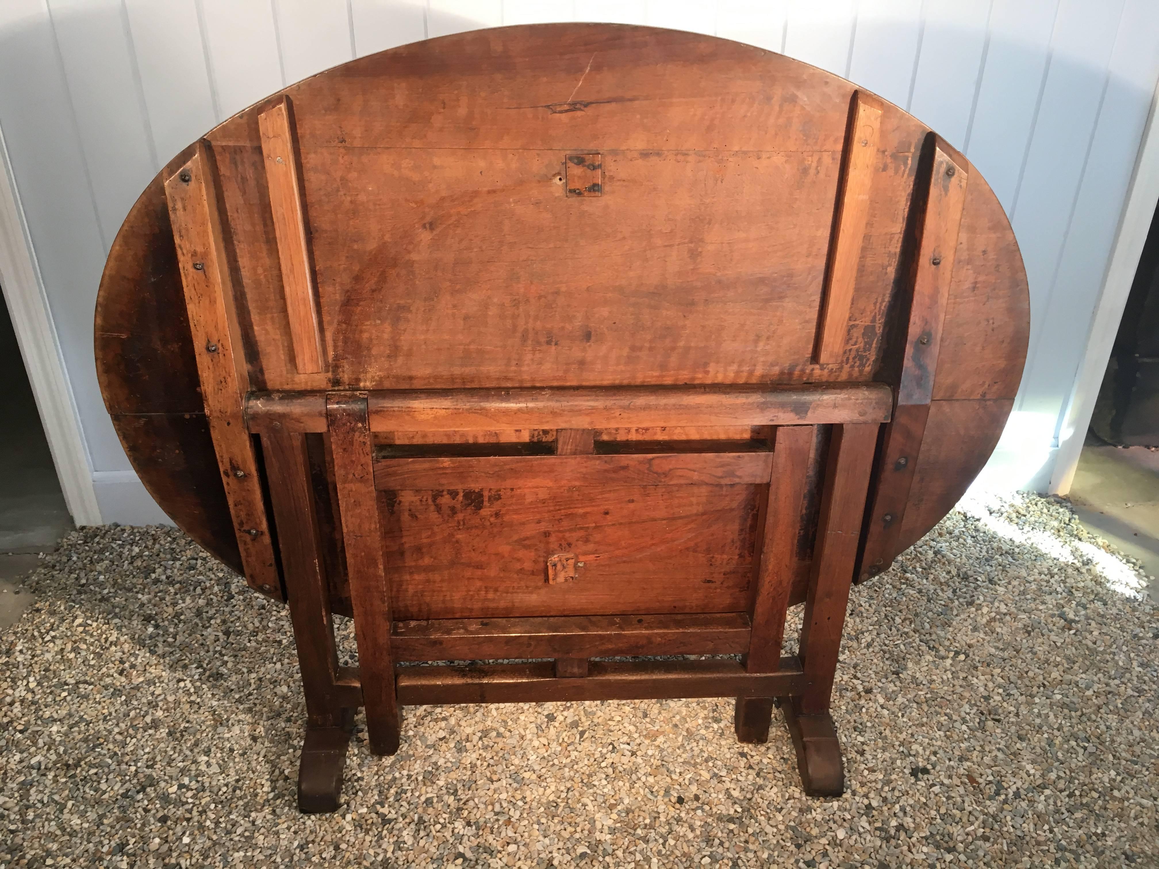 We love this walnut-topped vendange (wine-tasting) table for it's lovely waxed glow, easy storage (the tabletop tilts up) and seating for four. In wonderful, antique condition, there is a very small area of old wormwood loss to the inside of one of