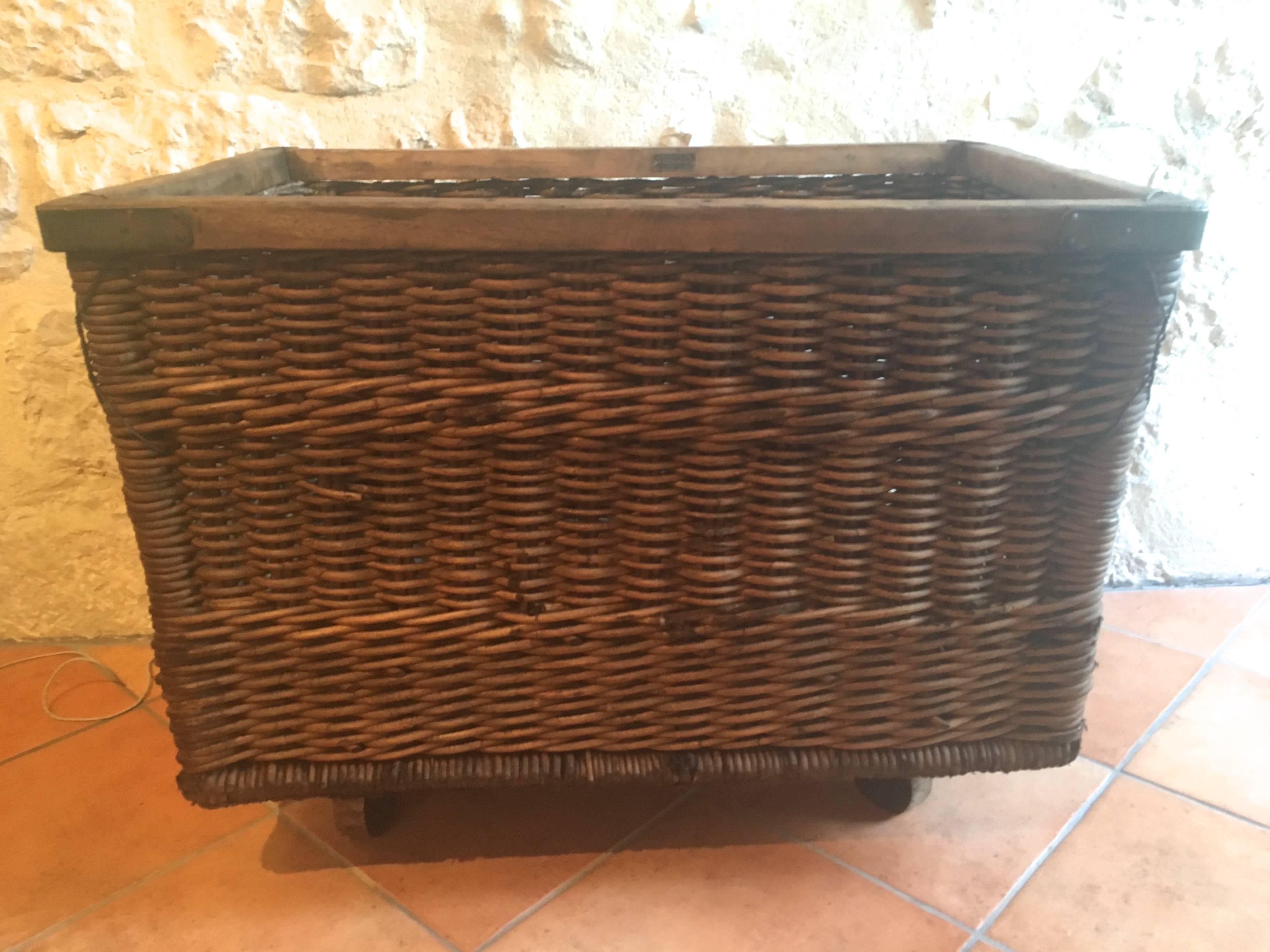 What a special piece! Used to transport baguettes from the bakery to shops, this large handwoven wicker basket has a sturdy wooden floor and working casters that make it a breeze to move. Wonderful as a storage bin for logs and kindling. Signed by