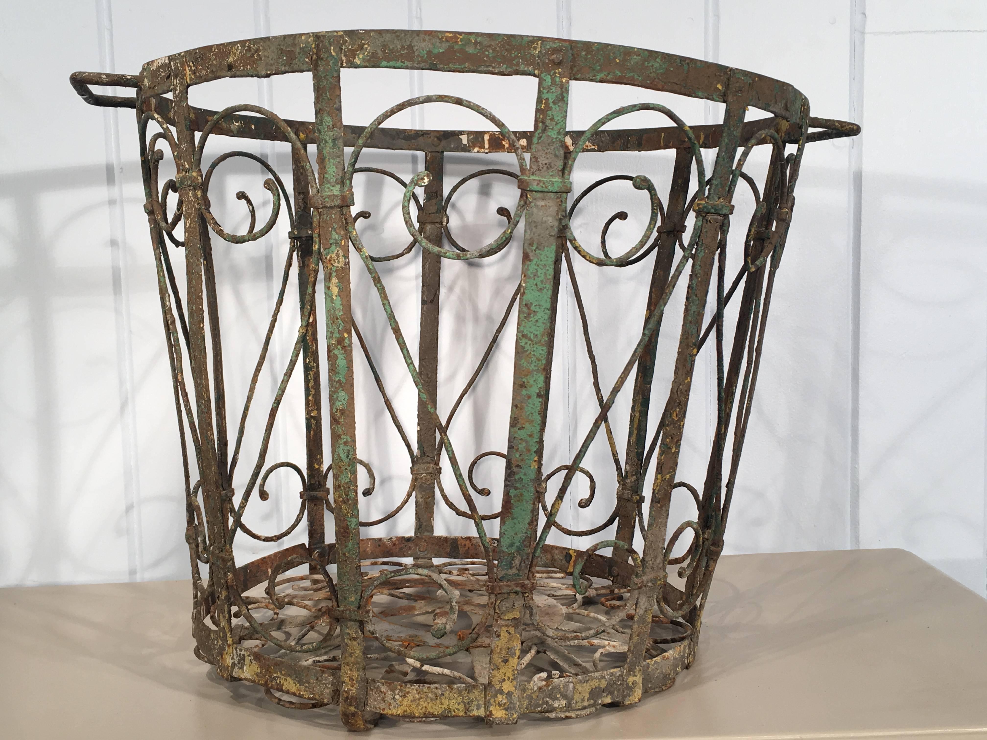 This lovely hand-wrought iron wastepaper basket has a very beautiful design, intricate wire-working and a stunning patina with original blue-green paint. There has been a repair to the bottom by a previous owner in the not so distant past that is