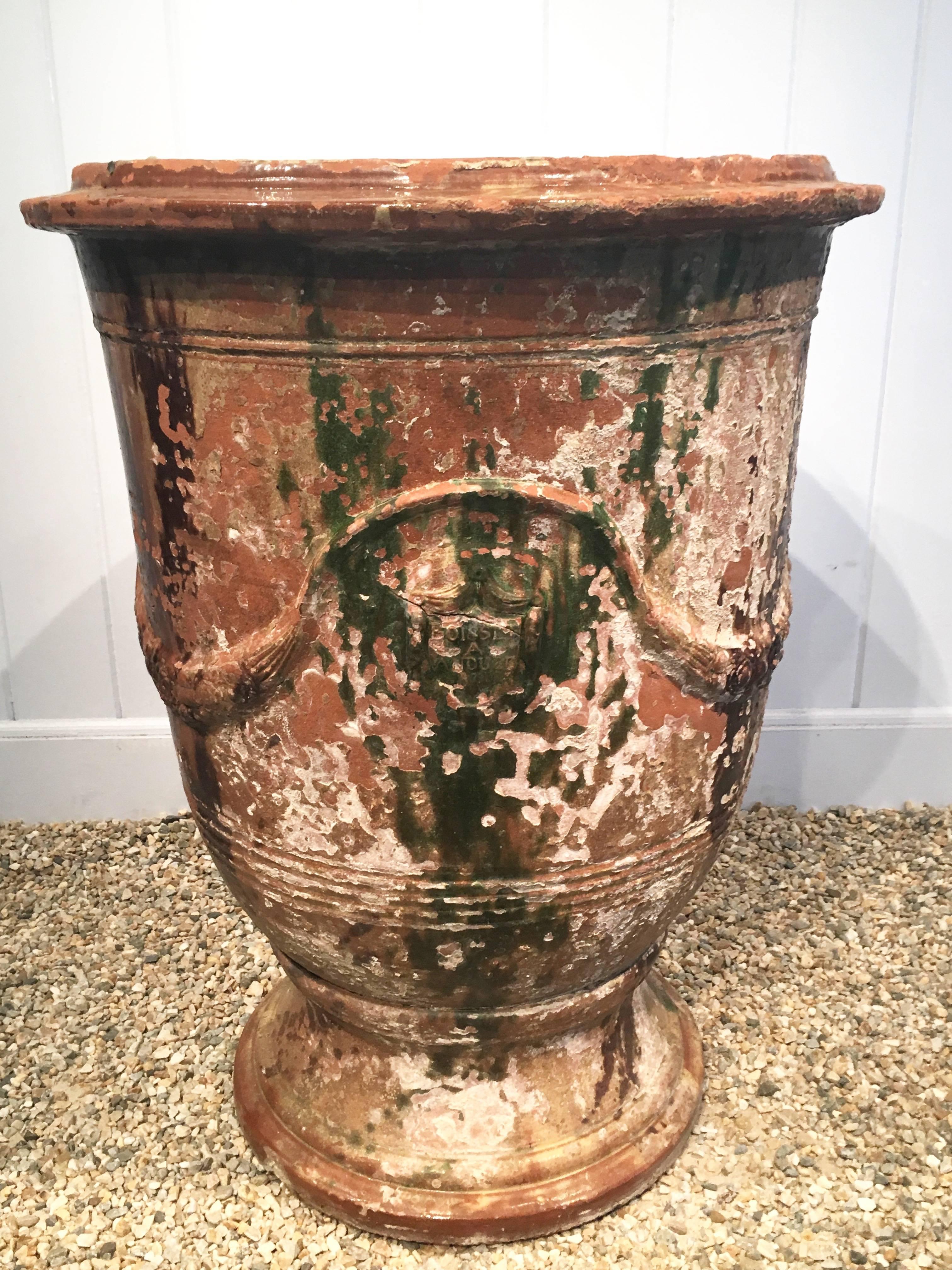 This stunning pair of "Vase d'Anduze" are larger than most and feature a marvellous worn glaze in shades of chocolate brown, emerald green, burnt orange, and butter yellow. With the traditional swags mostly intact, there is a fair amount