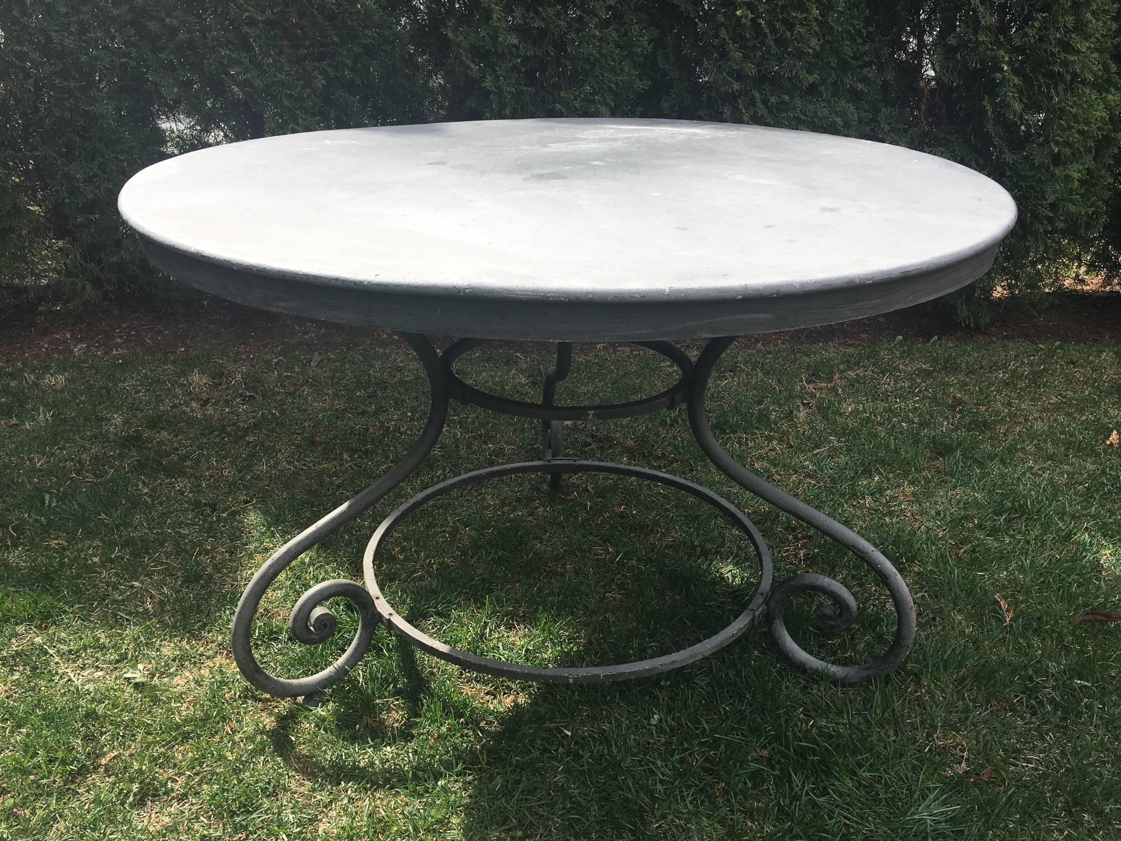This heavy steel table has classically scrolled legs and is finished in a medium gray matte paint with mild-moderate surface weathering and very minor chipping to the paint. Perfect in the garden as your dining table, it is solid and level and will
