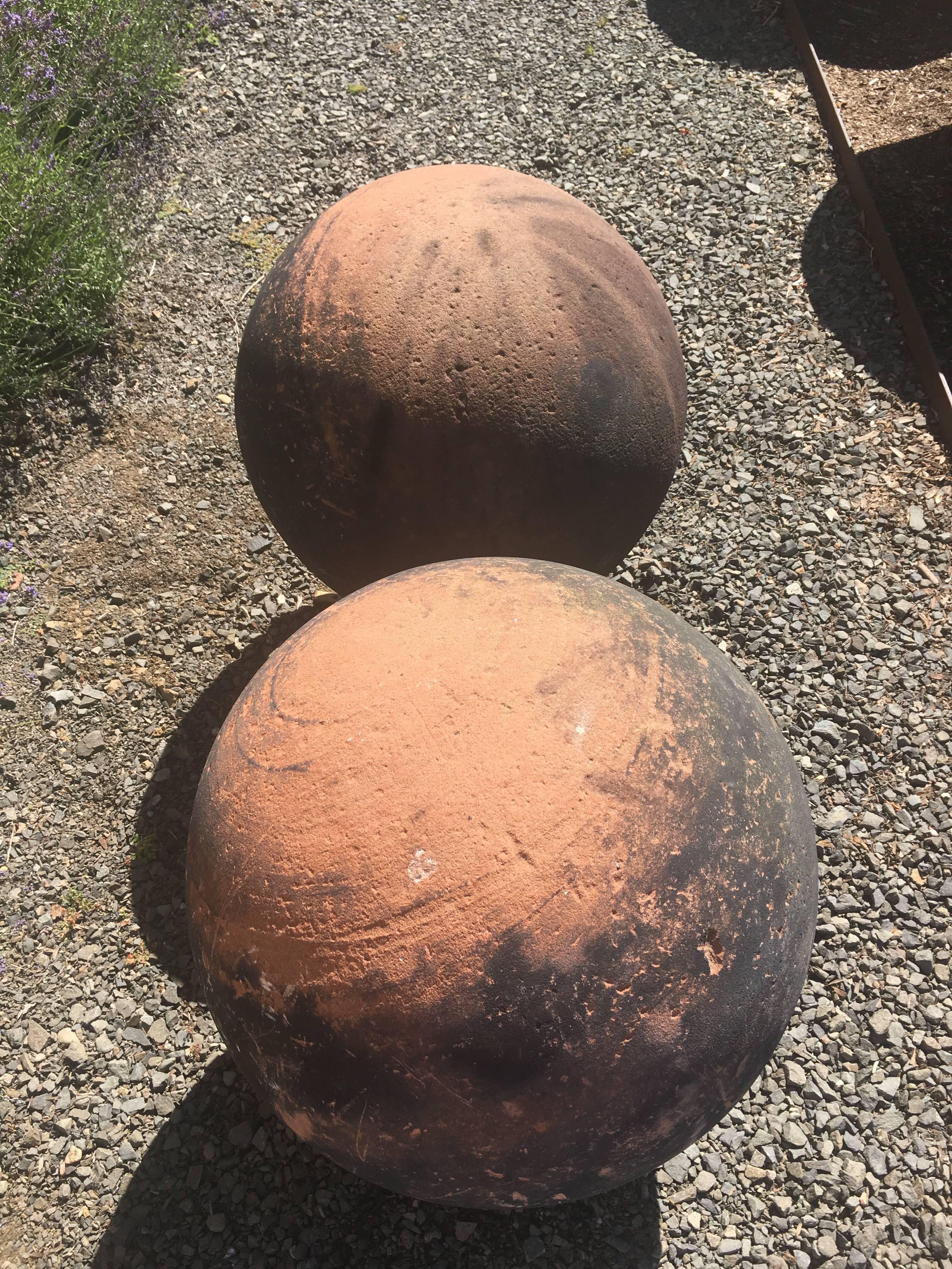 This is a magnificent and rare pair of very large carved red sandstone balls with verdigris bronze feet. Over the years, they have developed an amazing patina that, to our eye, resembles the planet Jupiter, and the combination of blackened coal dust