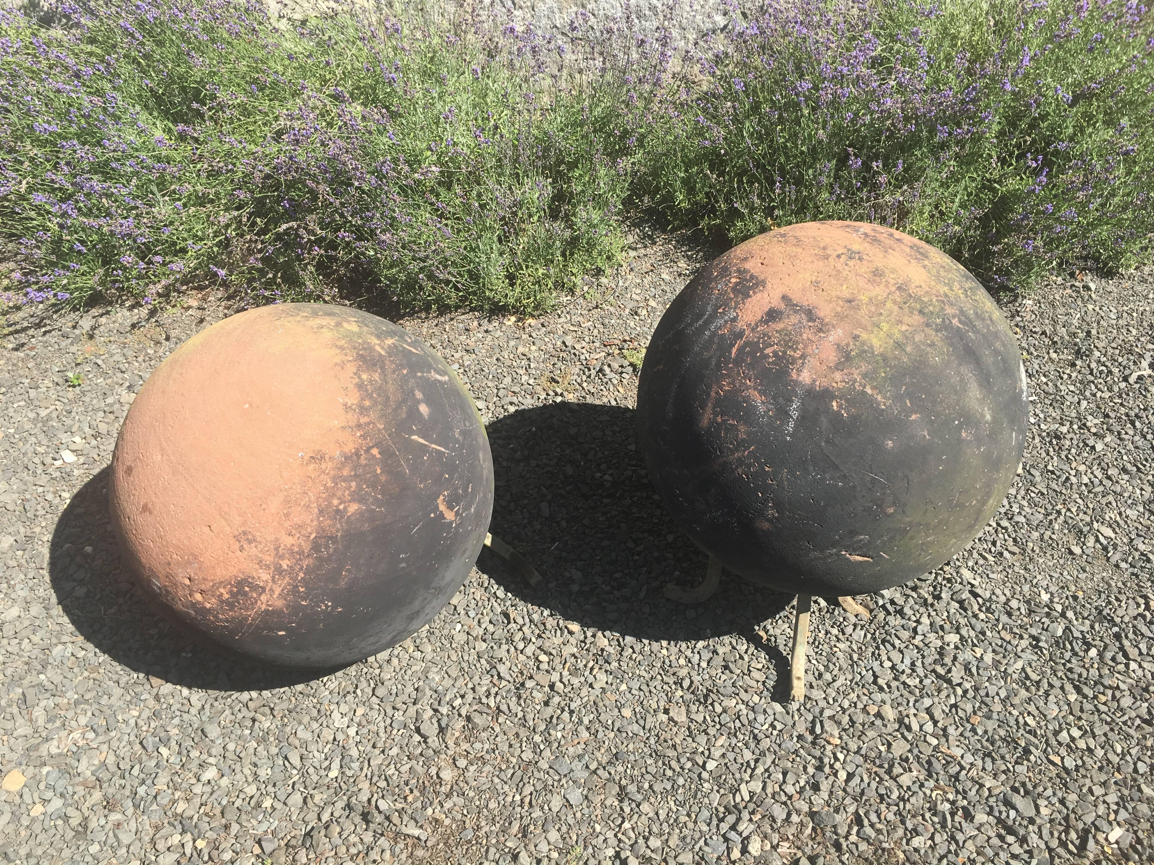 This magnificent and rare pair of very large hand-carved red sandstone balls has verdigris bronze feet. Over the years, they have developed an amazing patina that, to our eye, resembles the planet Jupiter, and the combination of blackened coal dust