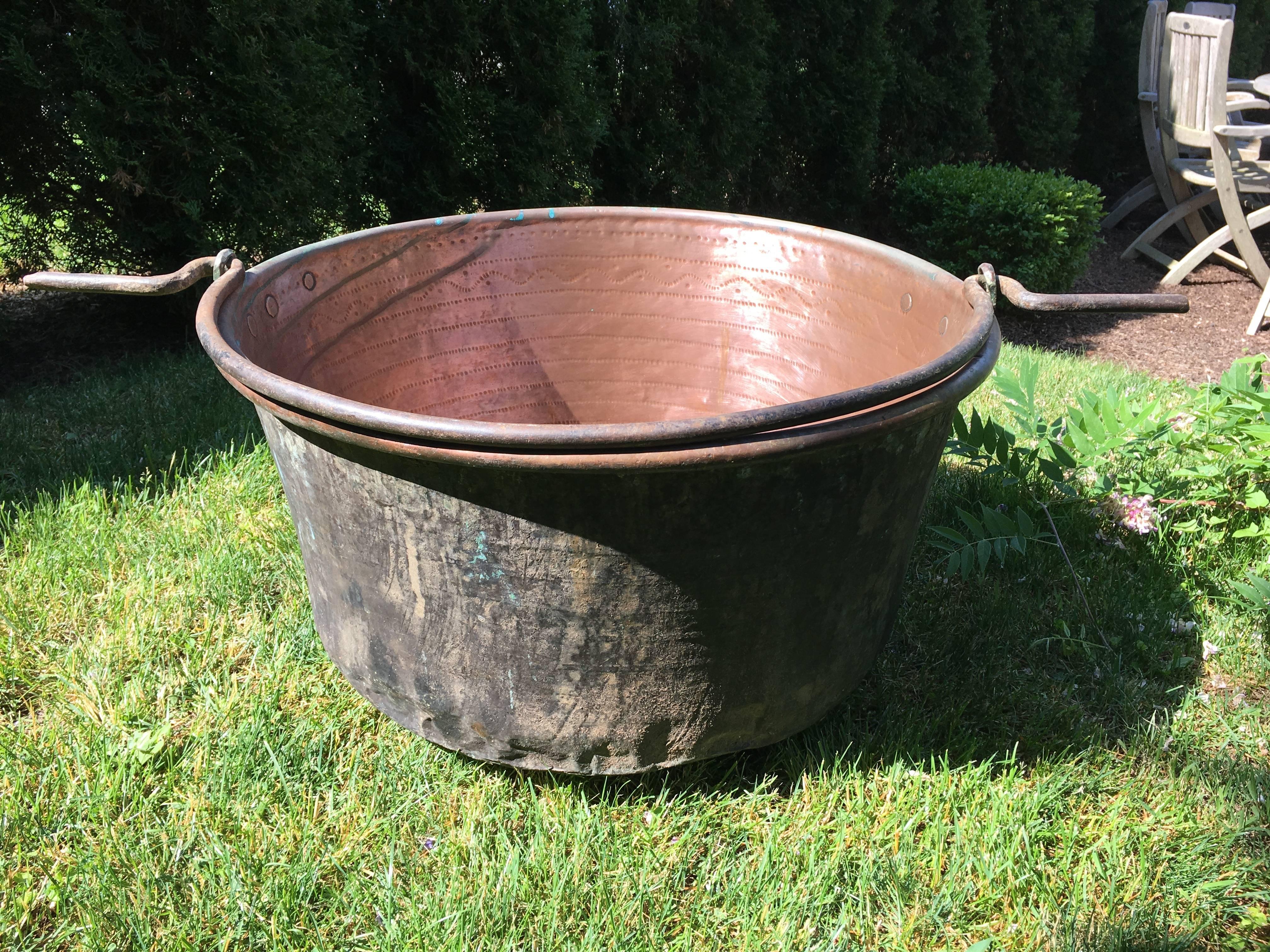 What a beauty! This large handmade copper cauldron has a thick iron handle that extends on either side and the inside has been polished to a brilliant finish. All hand-chased on the interior with exquisite detail, we have left the original dark