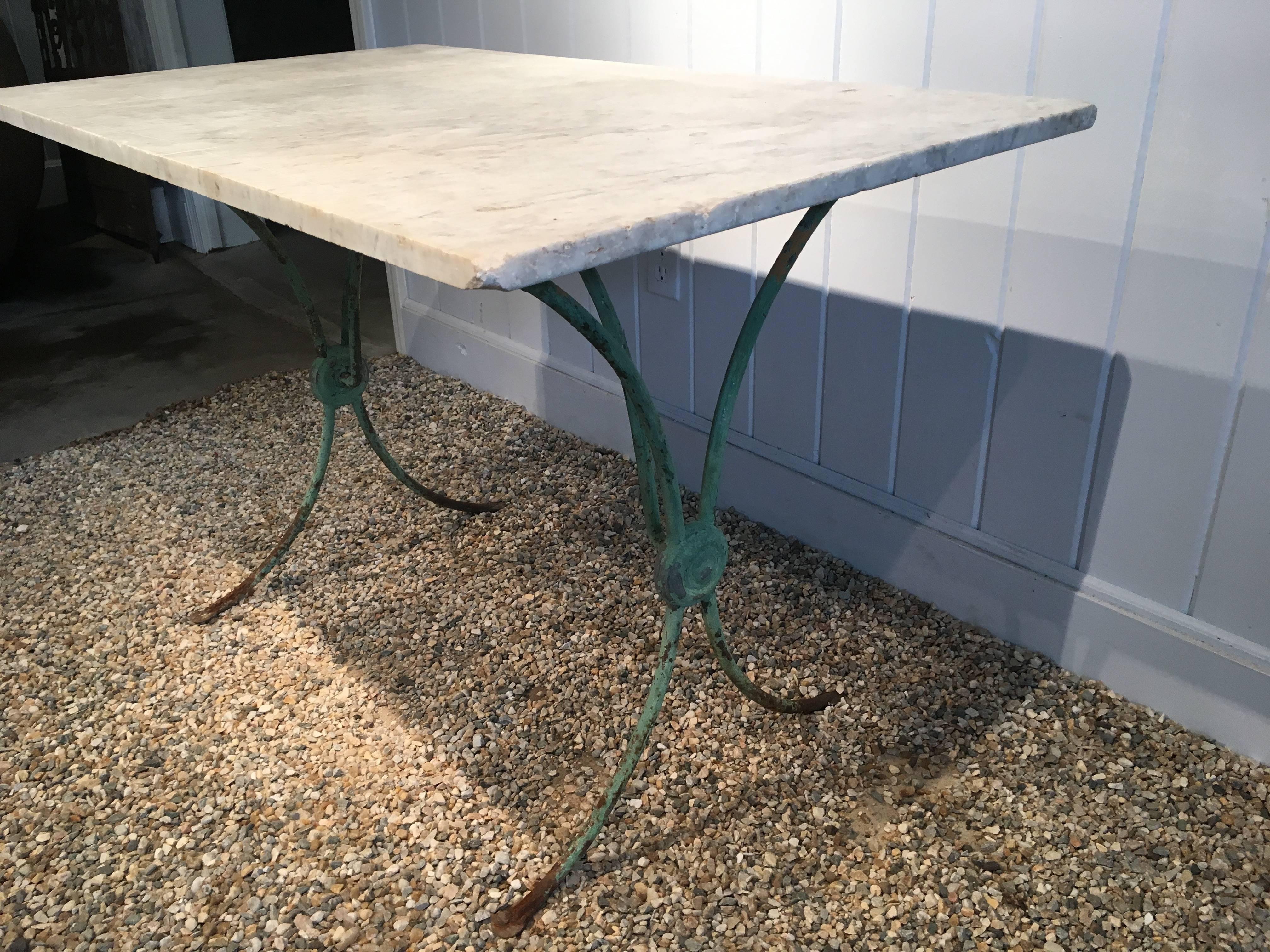 It is rare to find such a beautiful table in wrought iron with sweeping legs and center medallions on each side, and this one is a beauty, sporting old green paint in a lovely color. The marble top is antique and, while in very good condition