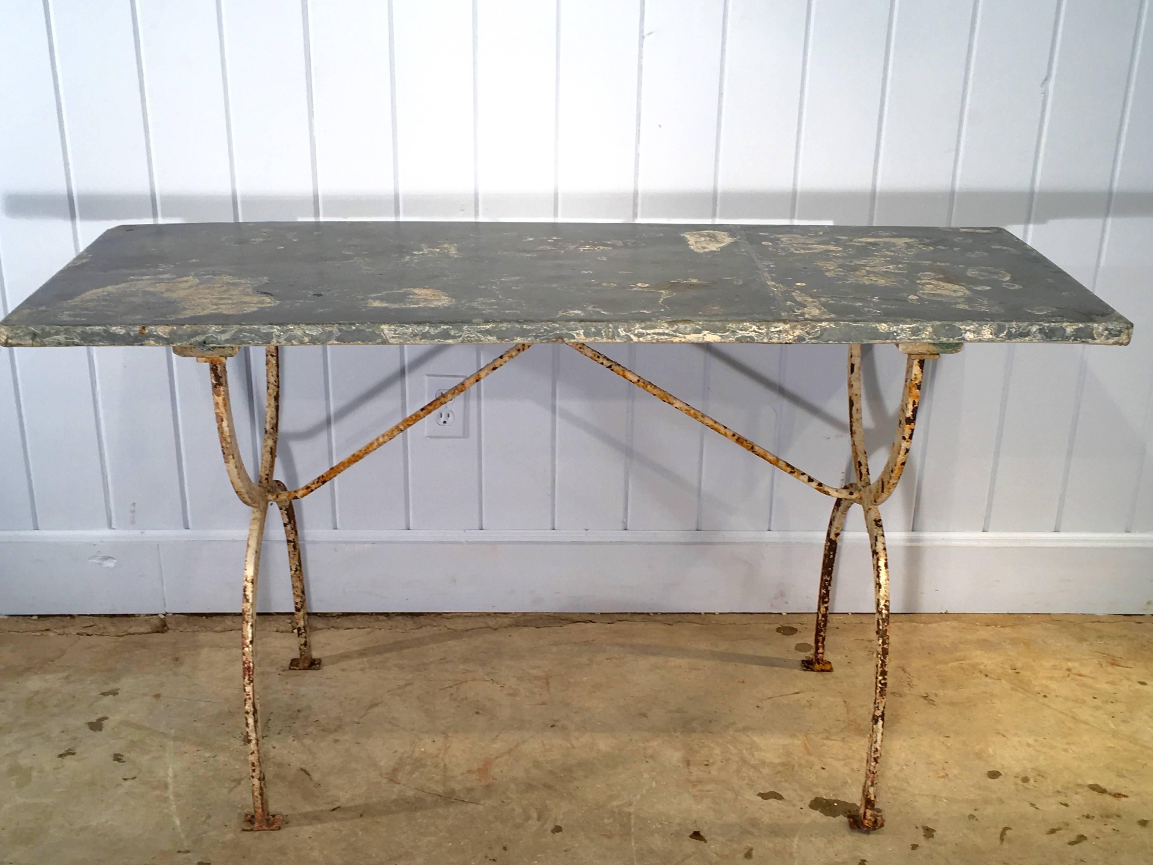 It is difficult to source old and weathered authentic zinc-topped tables and we found two beauties, very close in size. This is the taller of the two (the shorter one has sold). Both have identical wrought-iron bases in an old creamy white painted