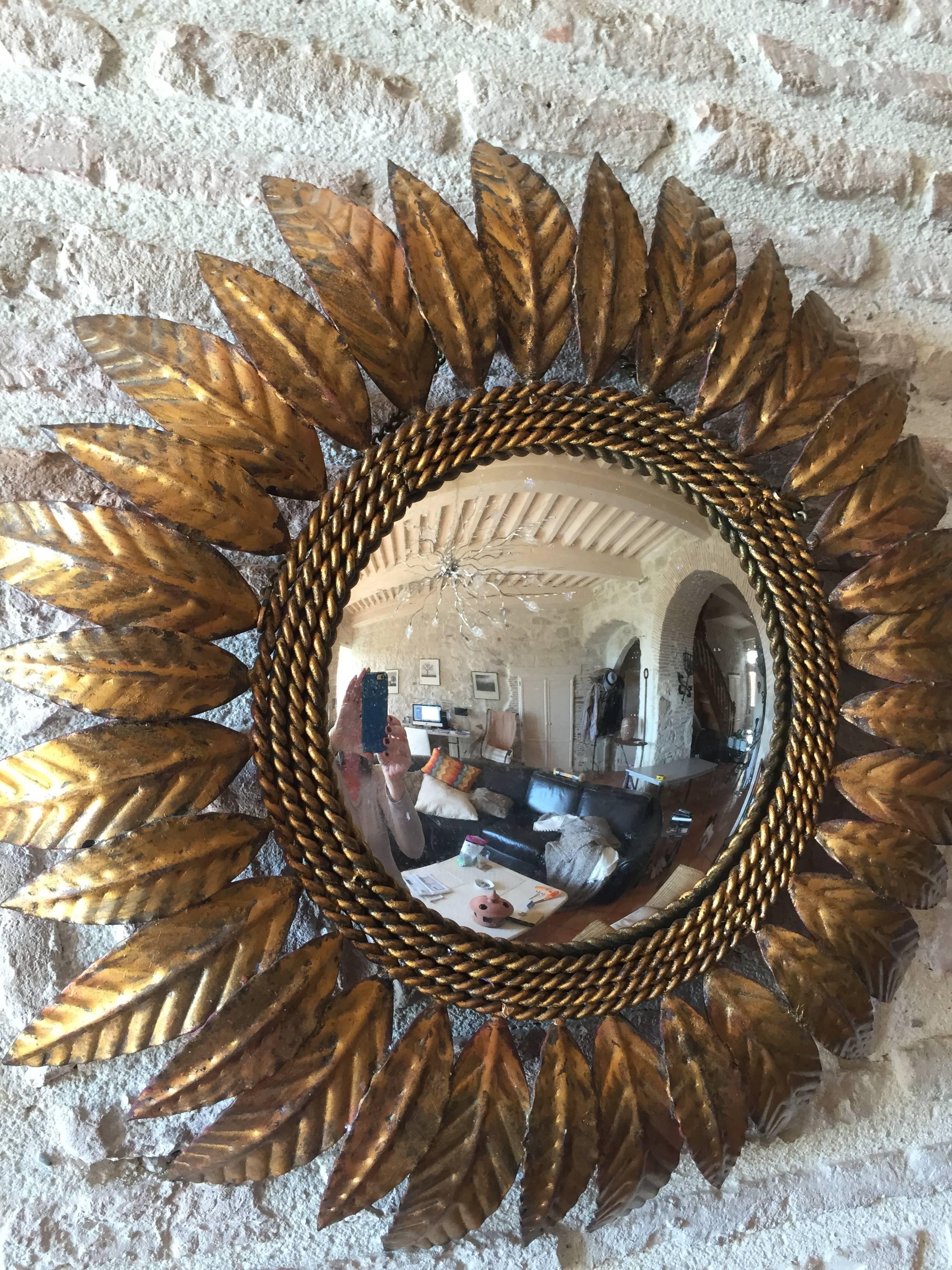 This stunning sunburst mirror in gold-painted iron is a lovely size and features convex bulls-eye glass, a nicely-patinated surface and four concentric circles of roping decoration between the mirror and the leaves. In all-original condition with