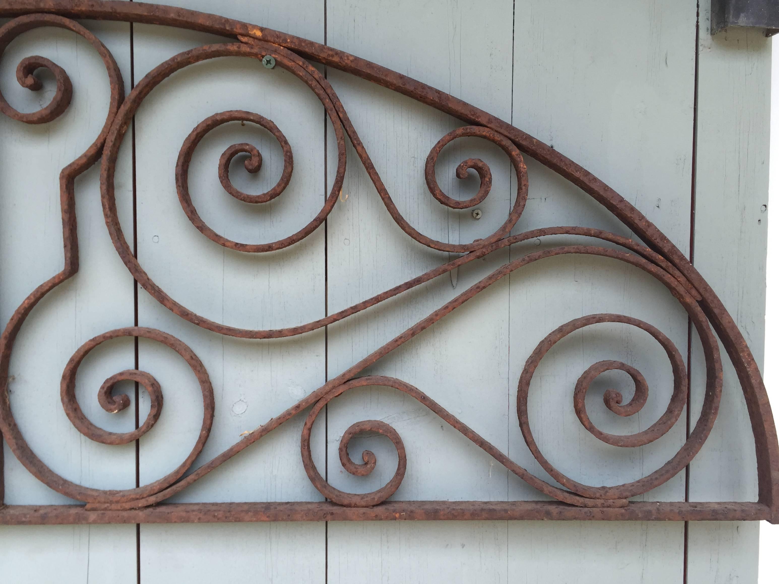 We think this large wrought iron demilune elliptical window grate in two parts actually served as a door overlight to a courtyard in Egypt or Morocco. Both were French colonies, and although the work is beautifully-done, it doesn’t quite have that