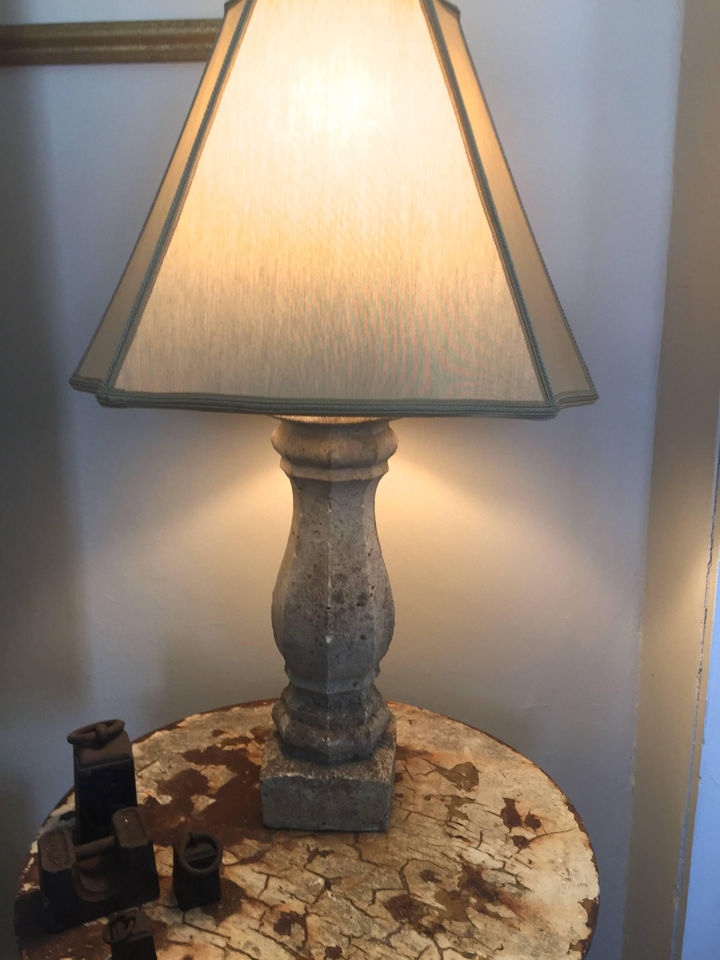 This elegant pair of cast stone lamps has an unusual and very pretty hexagonal baluster form, creamy color, and the heavily-weathered surface belies their age. Topped with cream color washable silk-like shades, the lamps are very versatile and work