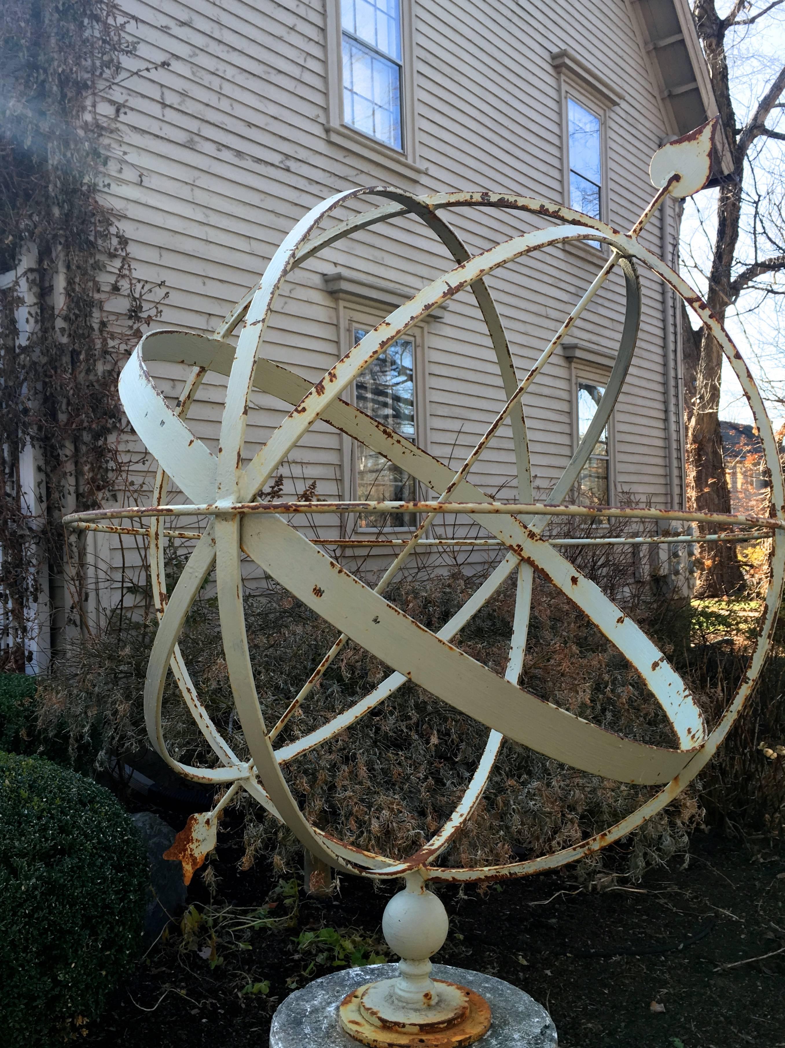This grand armillary is an impressive handmade contemporary one, but sits on a stone pedestal that dates to the 1930s. Simple and elegant of form, the armillary itself has been painted a neutral cream color and sports some rusting. It screws to the