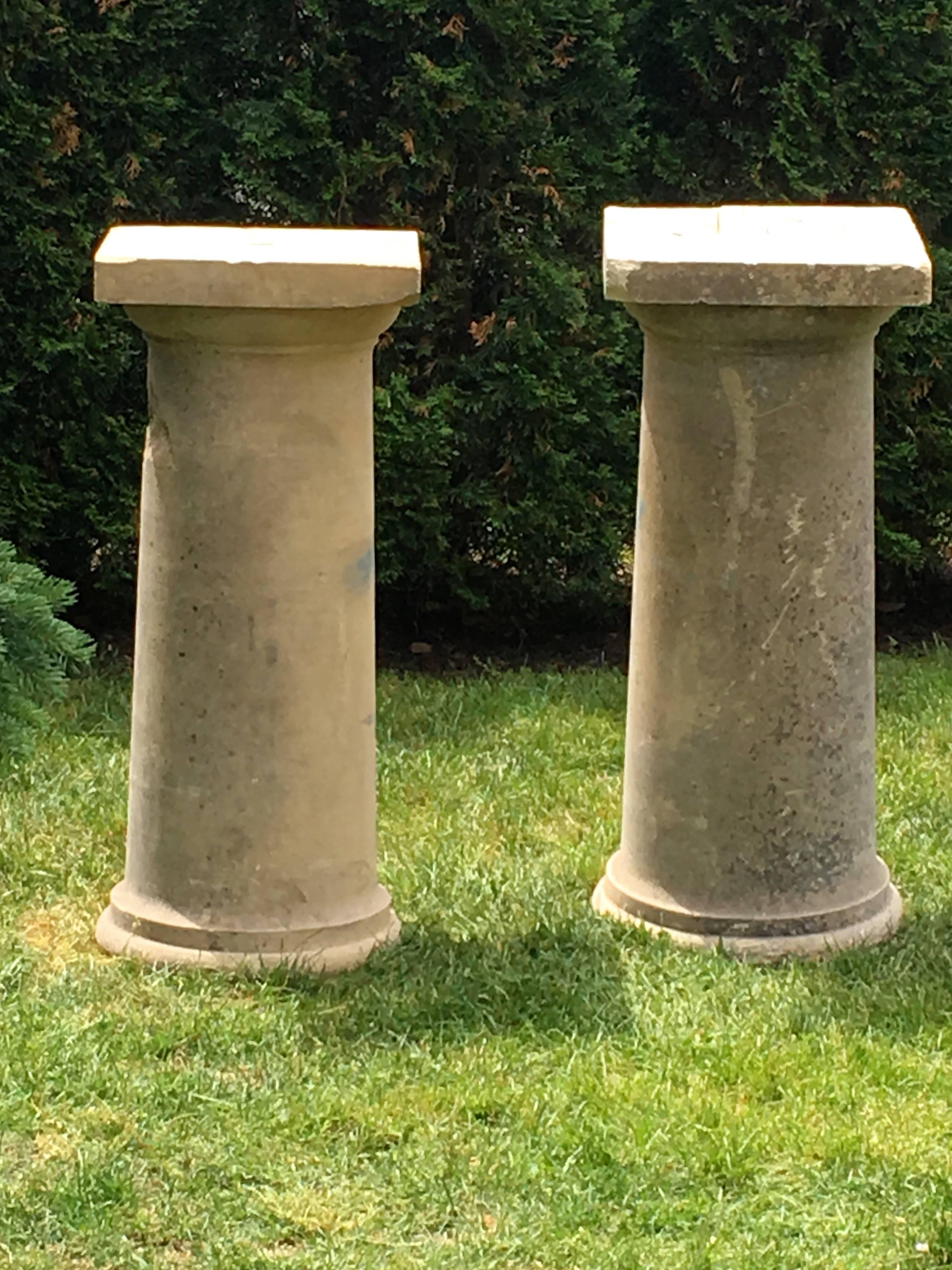 These impressive hand-carved stone pedestals/columns have an unusual form, as they are tapered cylinders with a round foot and larger square tops. The square tops have some damage that can either be restored, cut off, or left as is. The bodies have