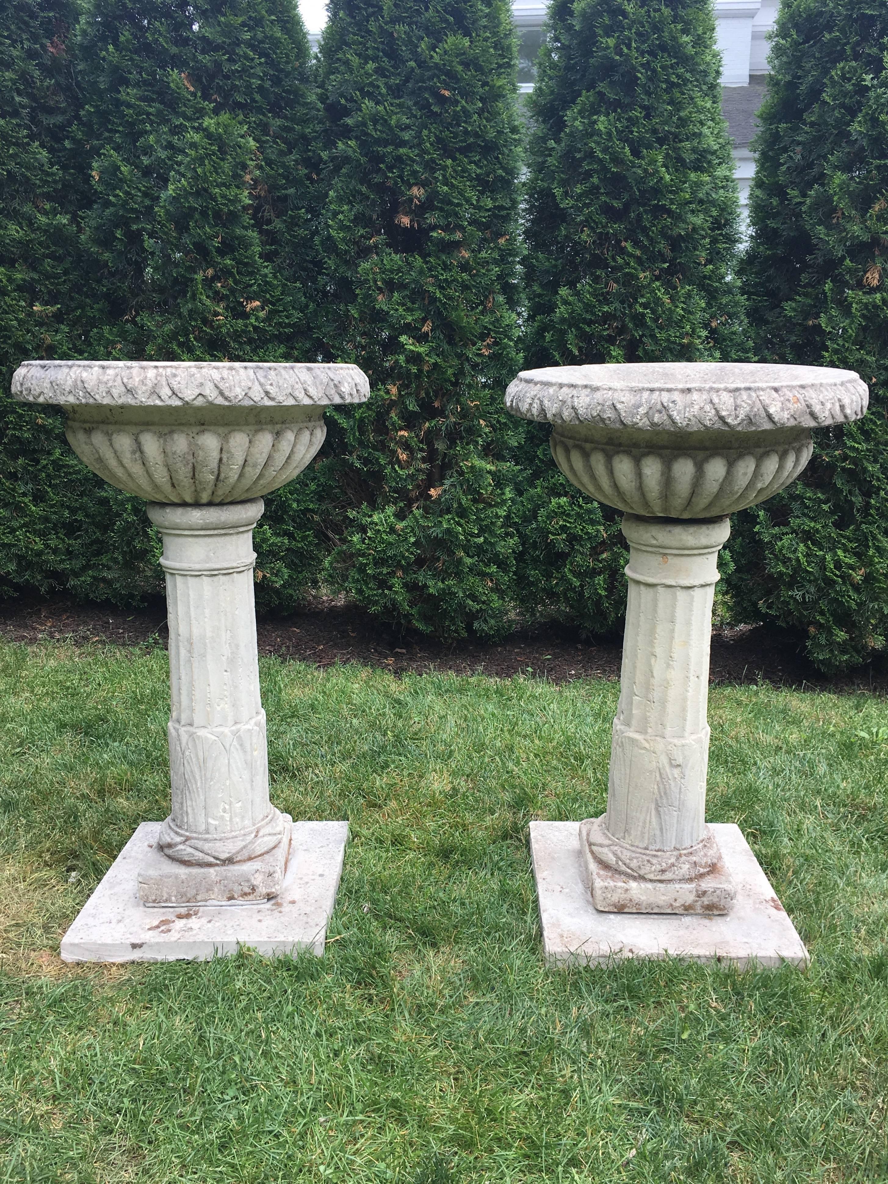 This rare and exceptional pair of carved limestone tazza-form urns on tall fluted pedestals have a storied provenance that dates to the late 18th C and Cornbury Park in Charlbury, Oxfordshire, owned at that time by the Duke of Marlborough. Unique