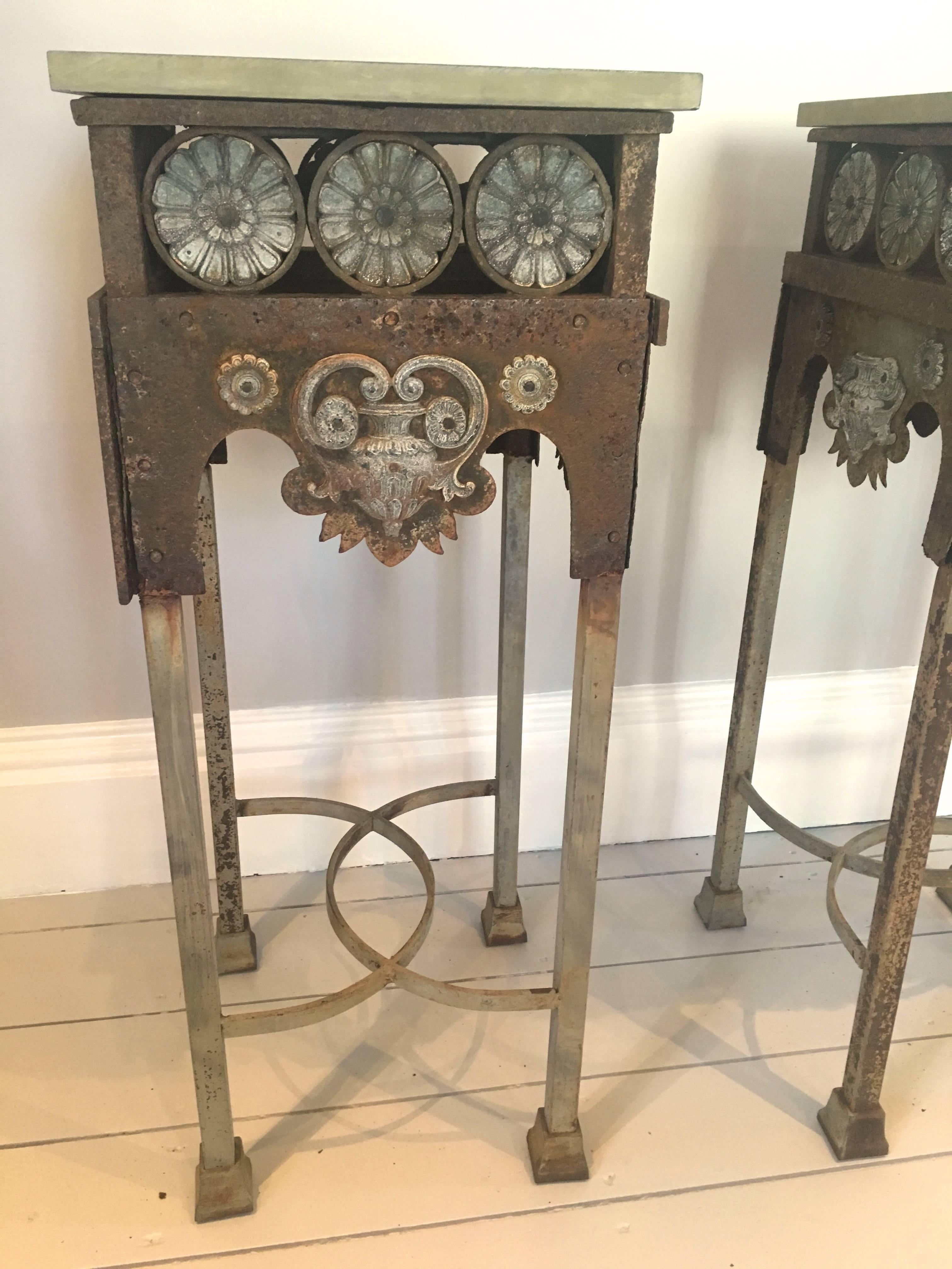 We believe these unusual and handsome stands to be a marriage of Gothic Revival riveted wrought iron and zinc bodies with later 20th century cast iron legs, stretchers and feet. The old wrought iron is well-worn and has thinned with minor losses in