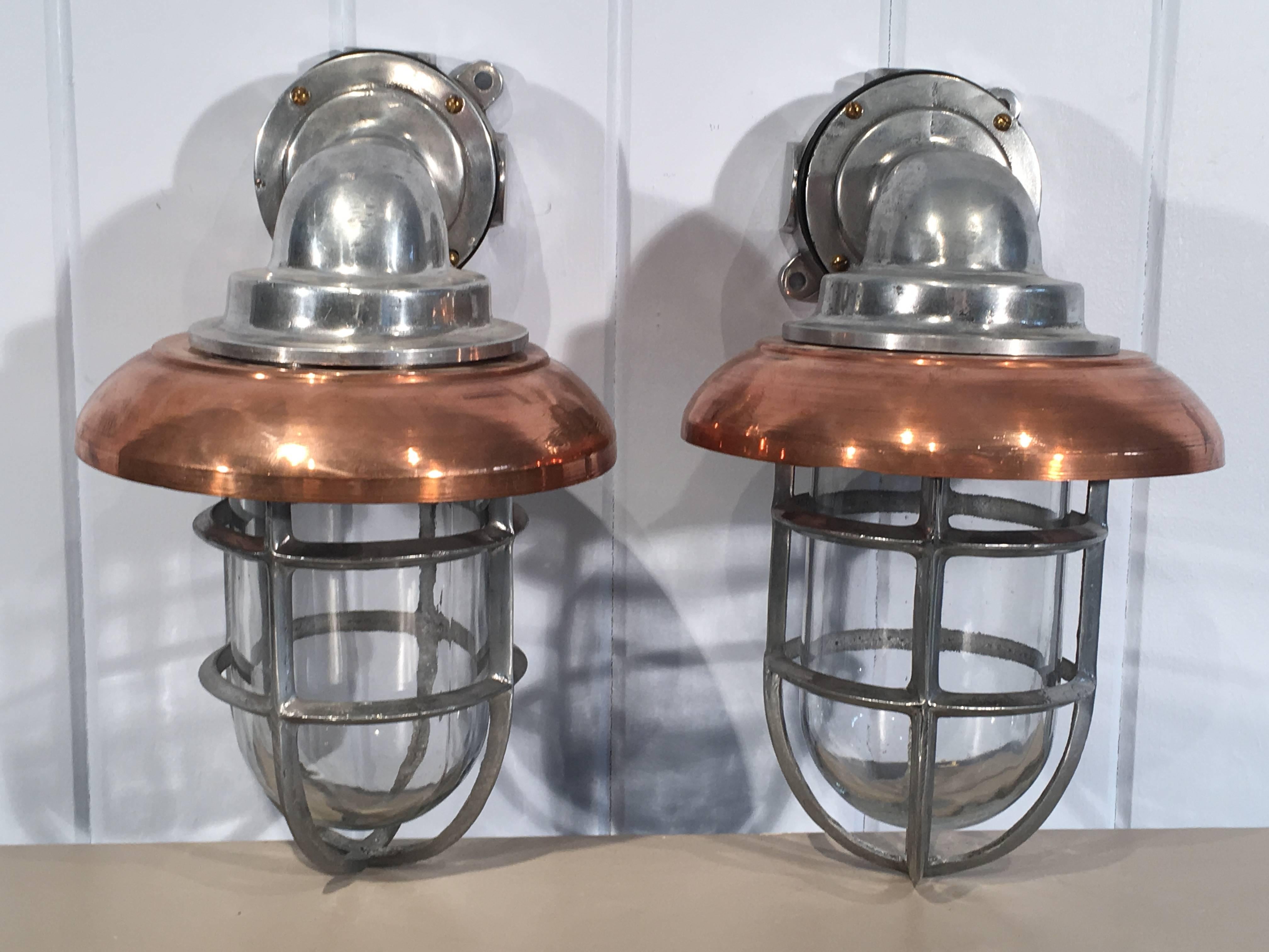 These polished aluminum ship's lamps have been completely restored and now sport removeable replacement copper shades. Their clean Industrial Design mixes well with a multitude of styles and they can be mounted indoors or out. Perfect in a bathroom