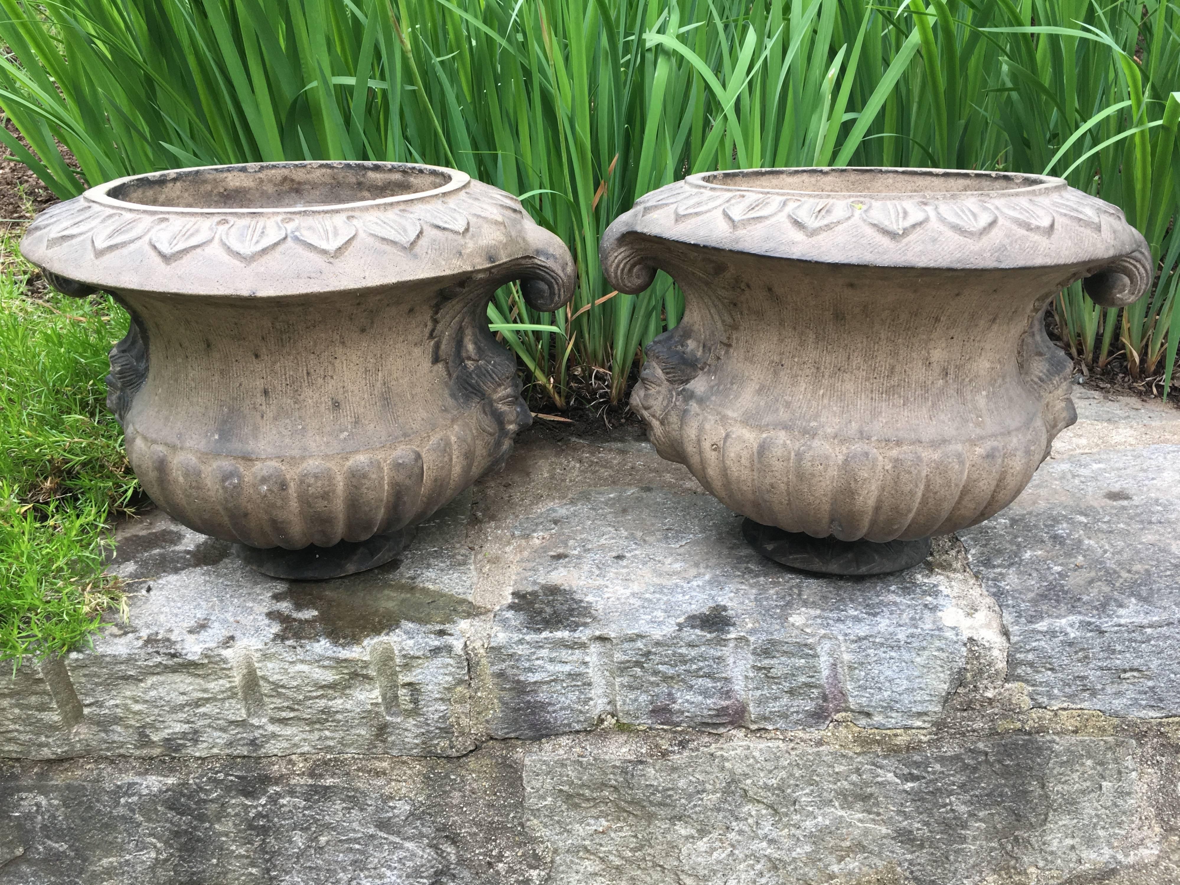 Although this rare and marvelous pair of "artificial stone" urns with masks and curled handles is unsigned, they do appear in the only surviving Pulham catalogue that dates to, circa 1920. The firm of James Pulham & Son was located