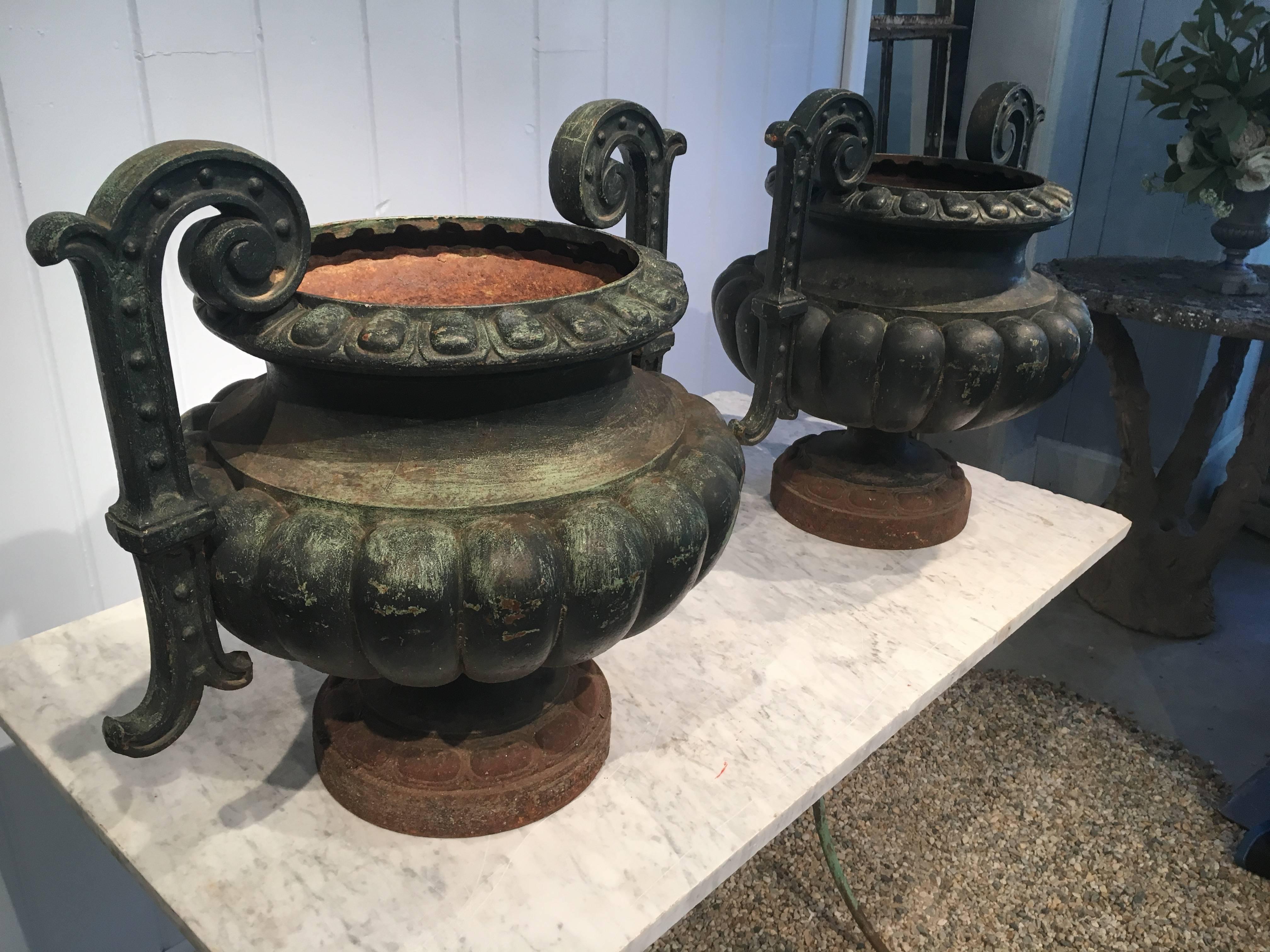 We love the classical melon form of these urns, embellished with scrolled handles and perfectly proportioned. Each sports old dark green paint and they are signed on their feet by their maker, Alfred Corneau and Sons. In wonderful condition, they