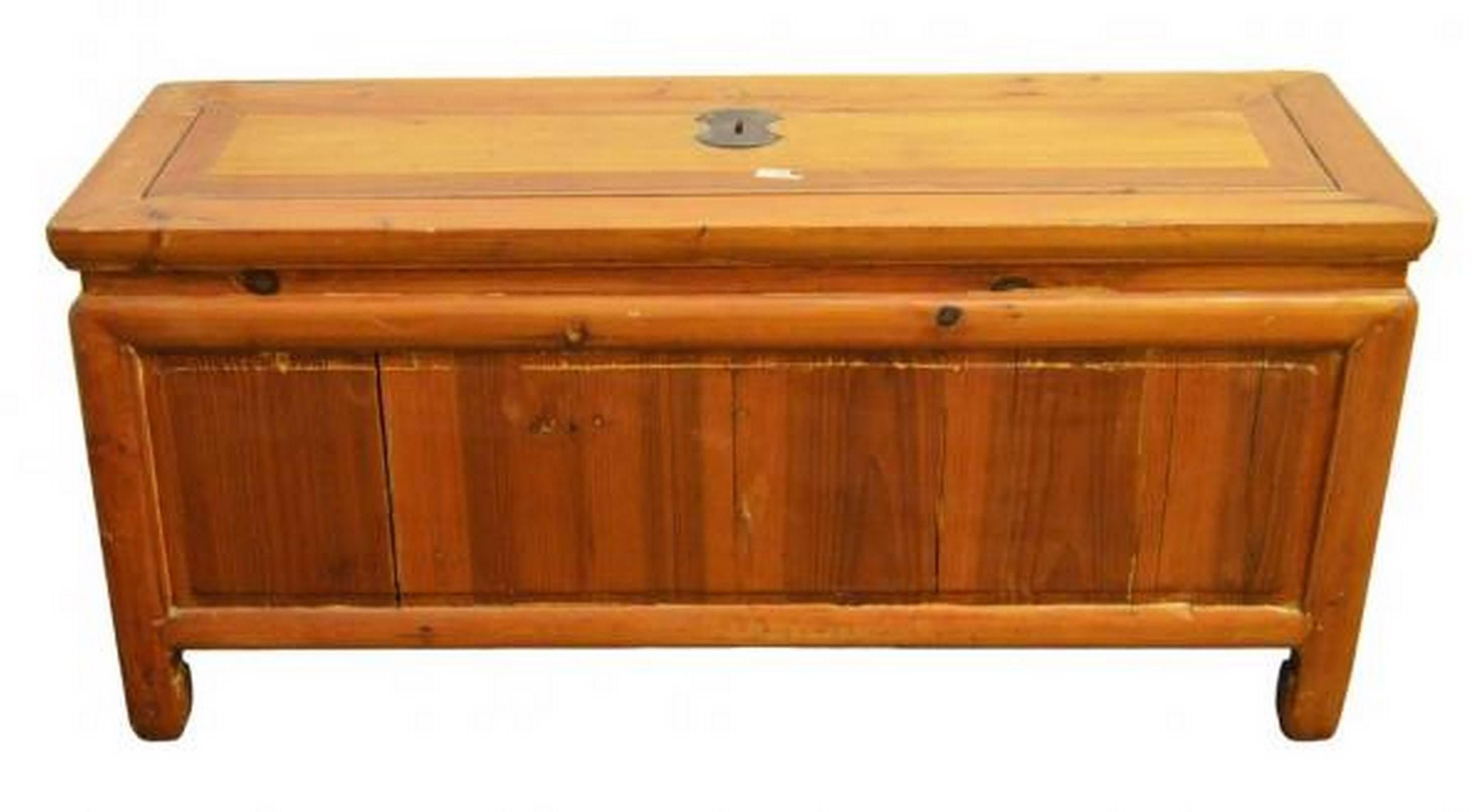 A Chinese 19th century low Kang chest displaying a natural patina and a light brown lacquer. This chest showcases a rectangle shape with an overhanging top and a recessed panel on its front. The wood grain is enhanced by the light brown lacquer