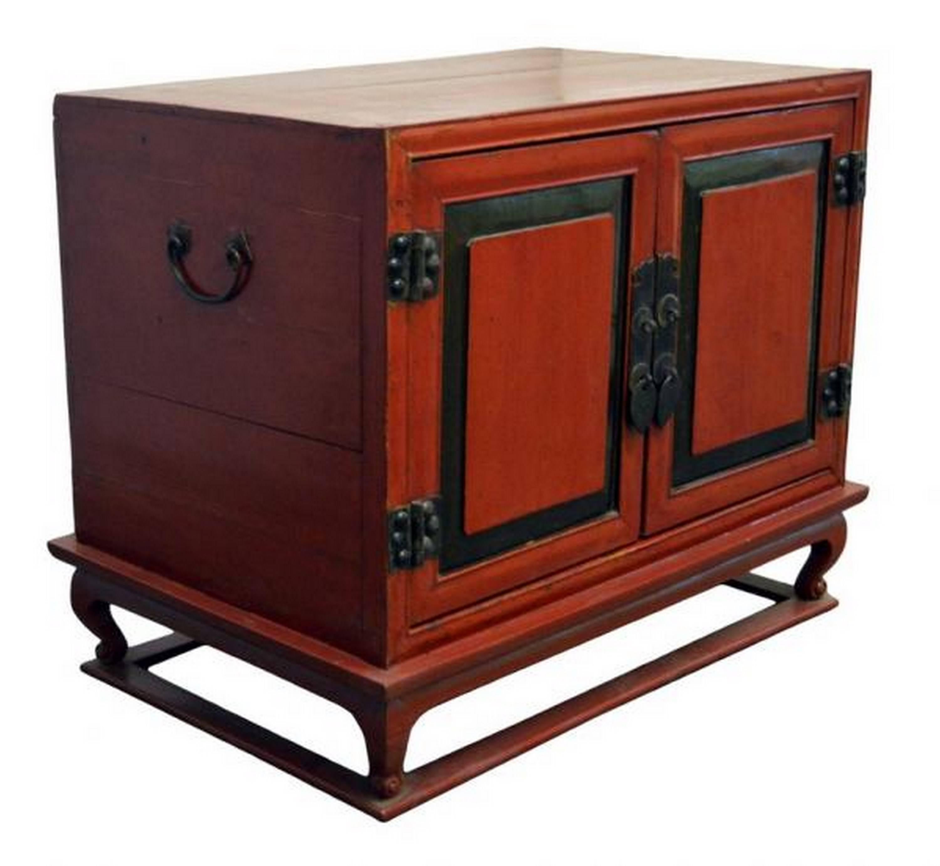 A mid-19th century Chinese bedside cabinet with red lacquered wood and brass hardware. This cabinet is made of a rectangular cabinet sitting on a base connected by four curved legs. Made of red lacquered wood, this cabinet features two doors adorned