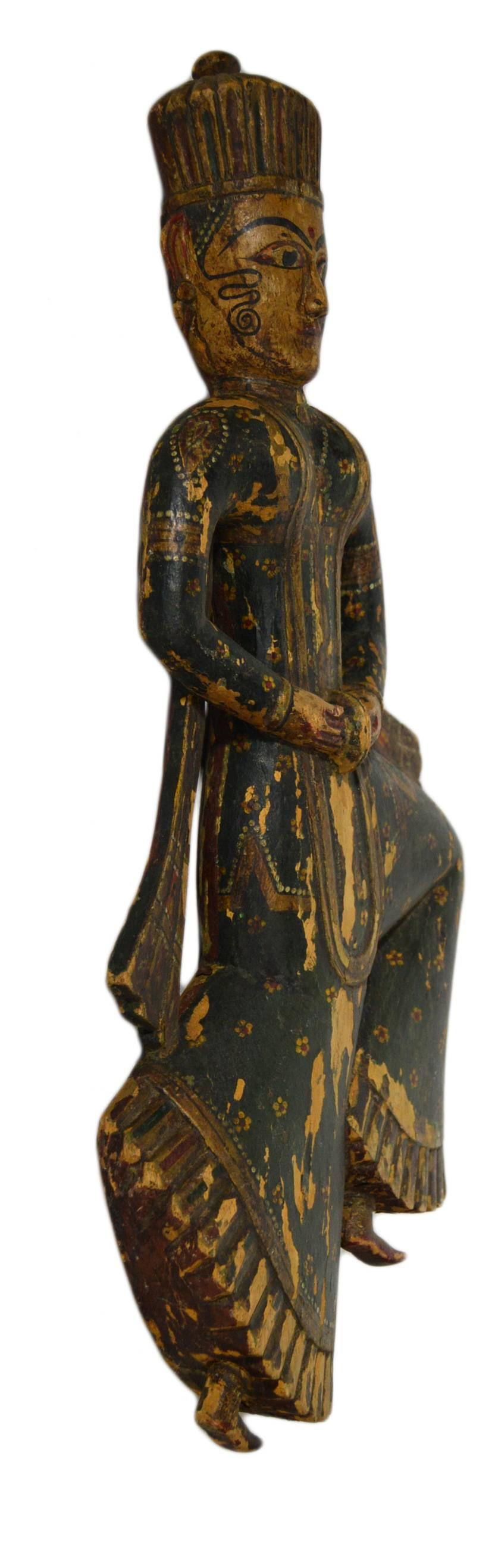 An antique temple statue carved and hand-painted in Indonesia in the early 20th century. This wooden statue shows an Indonesian dancing character. His dynamism is enhanced by his flying scarves and by his posture. The character wears black adorned
