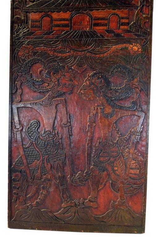 An Indonesian hand-carved wooden puppet show sign with red and black painted accents from the early 20th century. This Indonesian early 20th century sign was hand-carved in Indonesia for a puppet show. This tall panel is entirely carved in