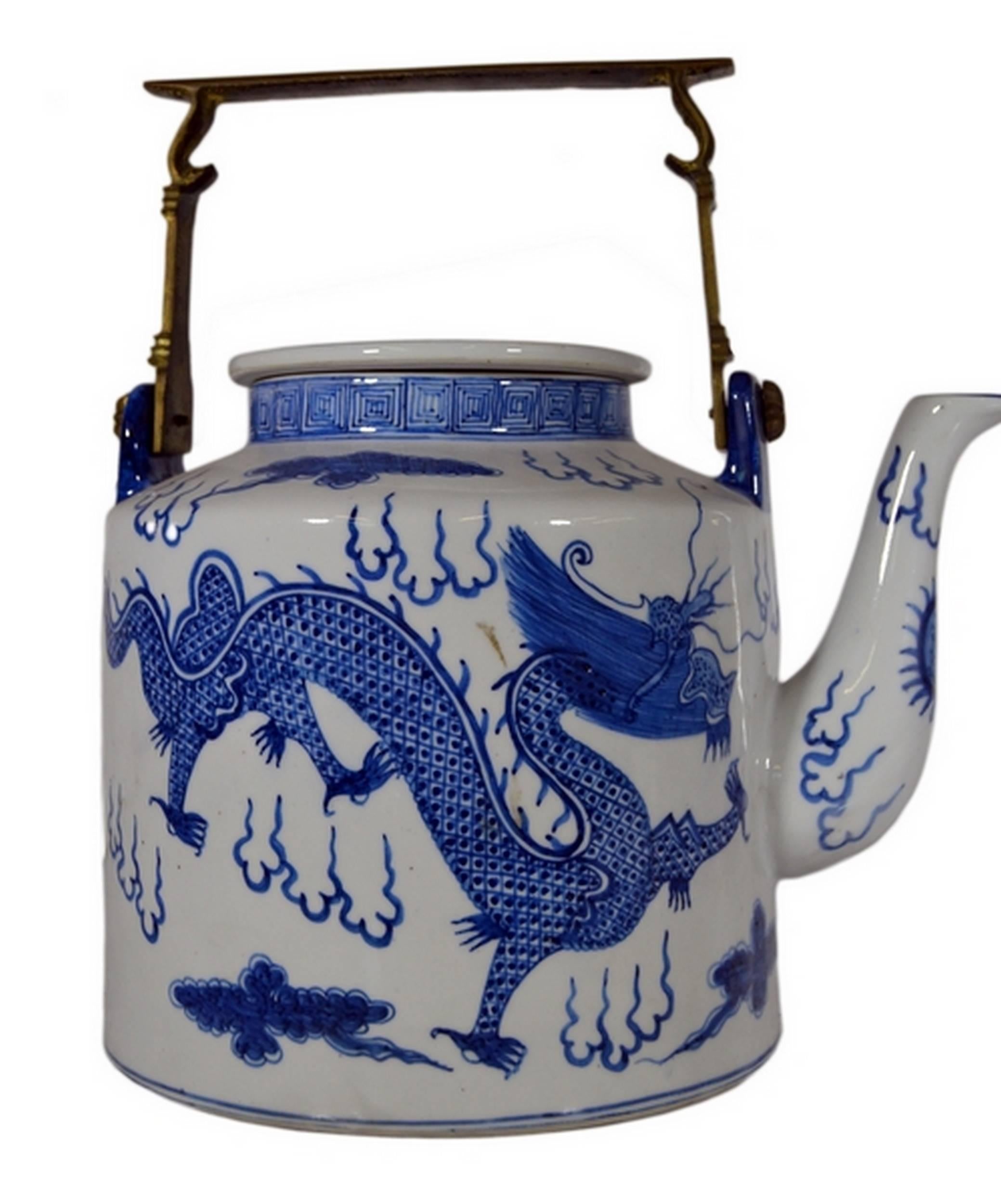 A vintage Chinese early 20th century teapot hand painted on porcelain with a blue and white technique. This teapot adopts a refined cylindrical shape with a spout, surmounted by a small neck and a carved brass handle. A stylized blue hand painted