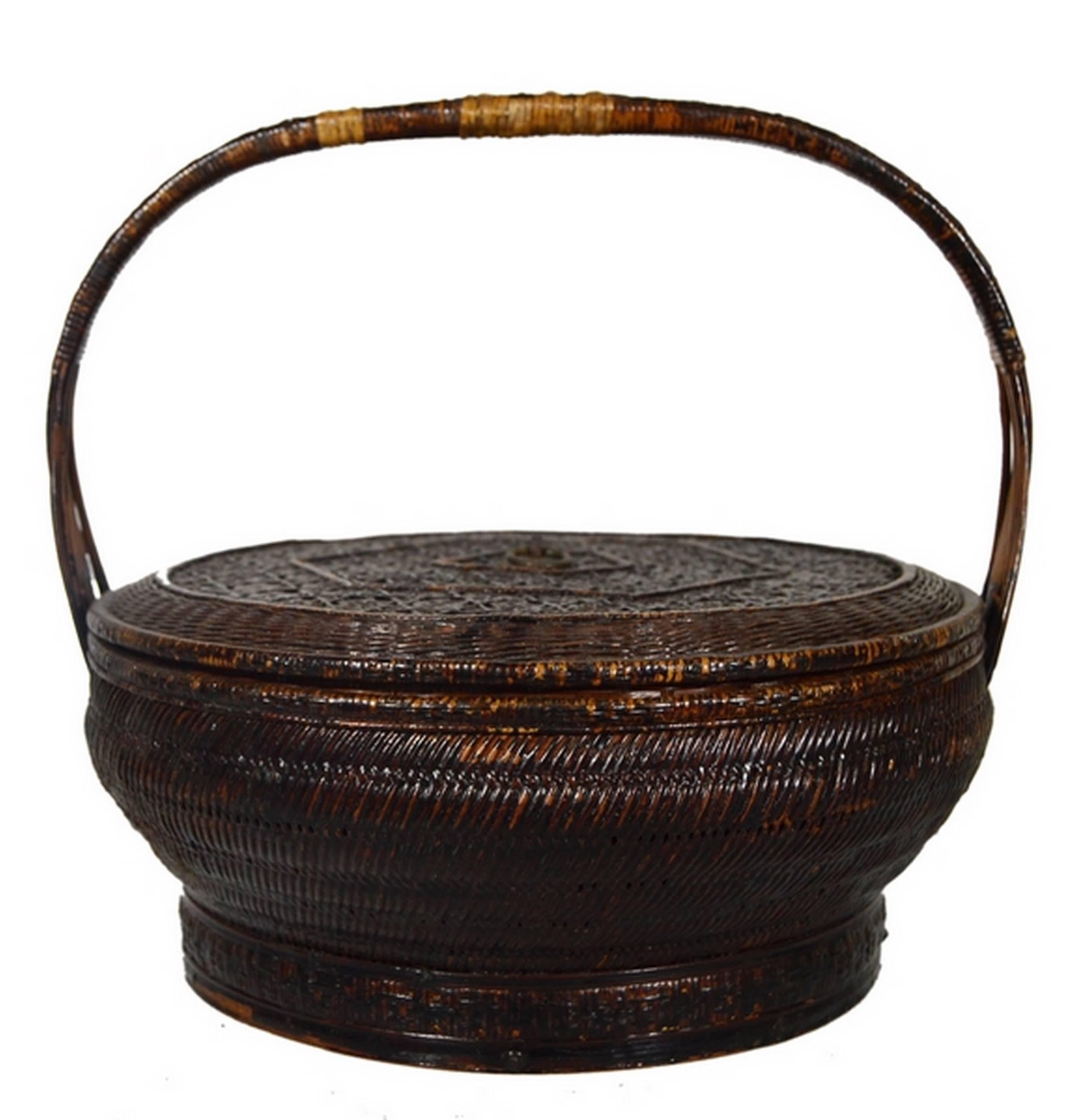 A small 19th century Chinese basket handwoven with rattan on a bamboo armature. This small round basket rests on a dark green painted base contrasting with its brown rattan exterior. The base is reinforced thanks to bamboo stretchers while the edge