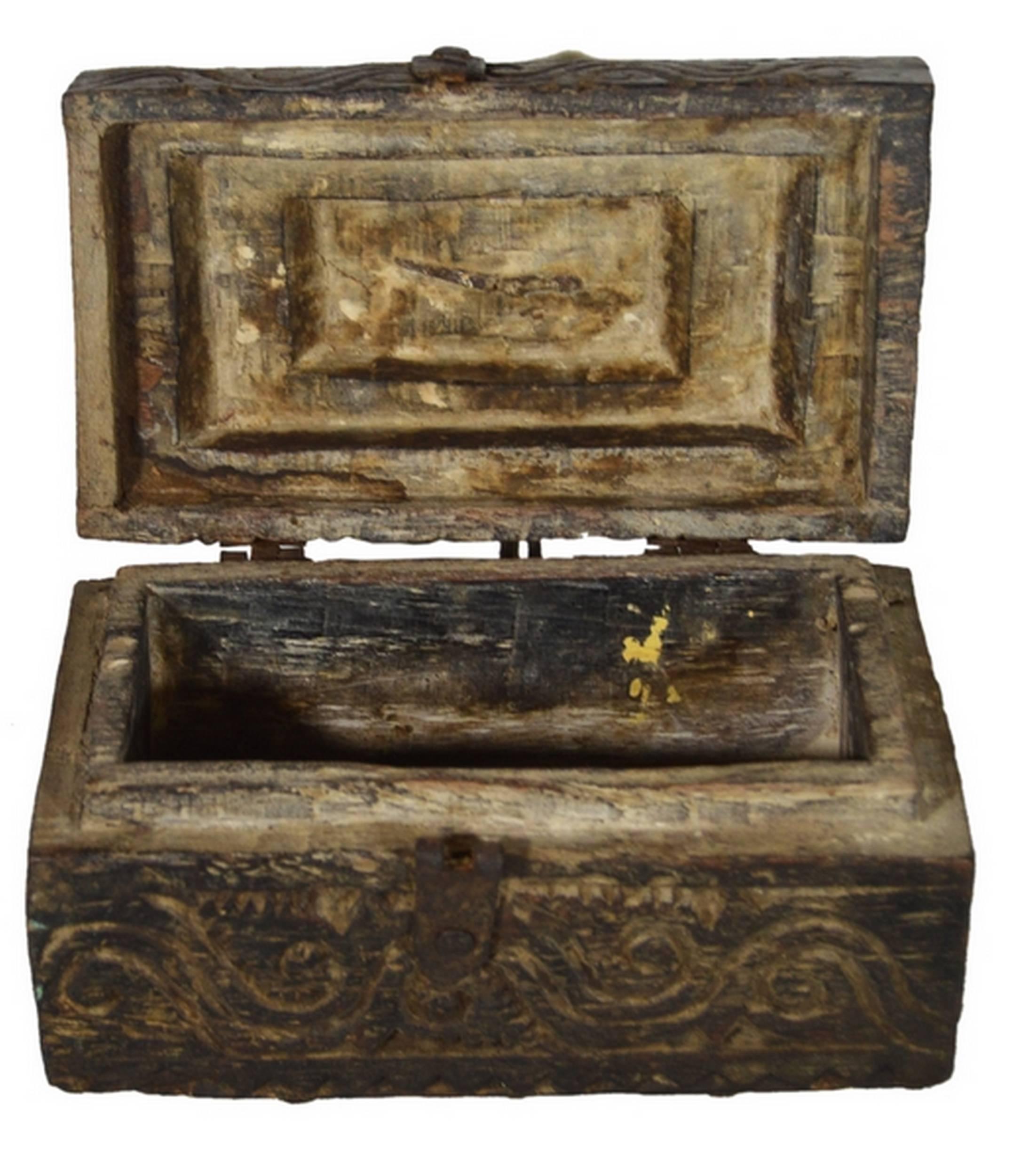 A handmade 19th century Indian money box with hardware and carved of wood. This small rectangular box displays a roof-shaped lid. Each side features carved wave and scroll patterns while the top showcases geometrical motifs. The lid opens thanks to