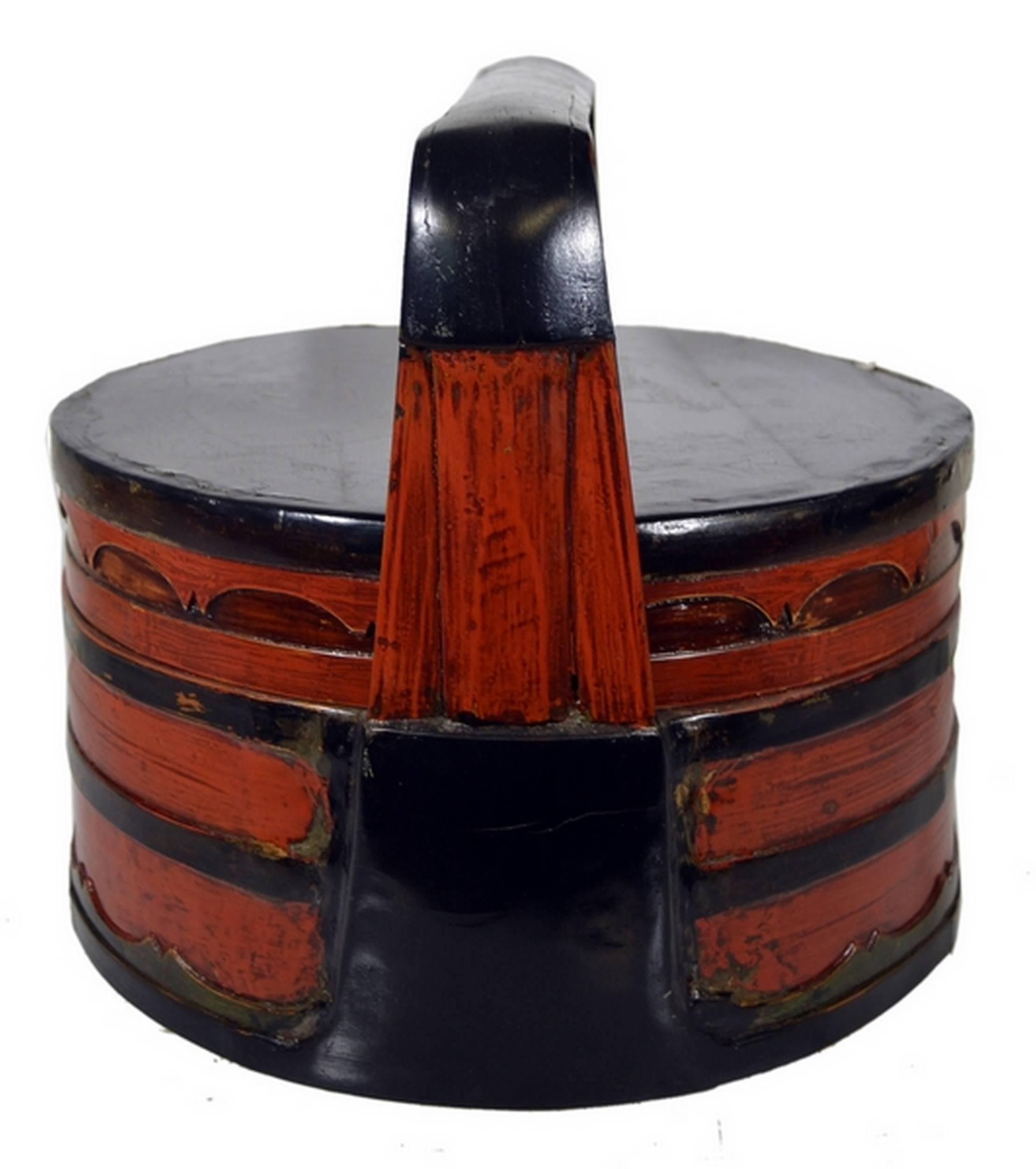 A 19th century Chinese tiered lunch basket made with two-colored bamboo and wood, and adorned with half-moon patterns. This basket features a stepped body, topped with a lid and a large rectangular handle. This basket was made with red varnished