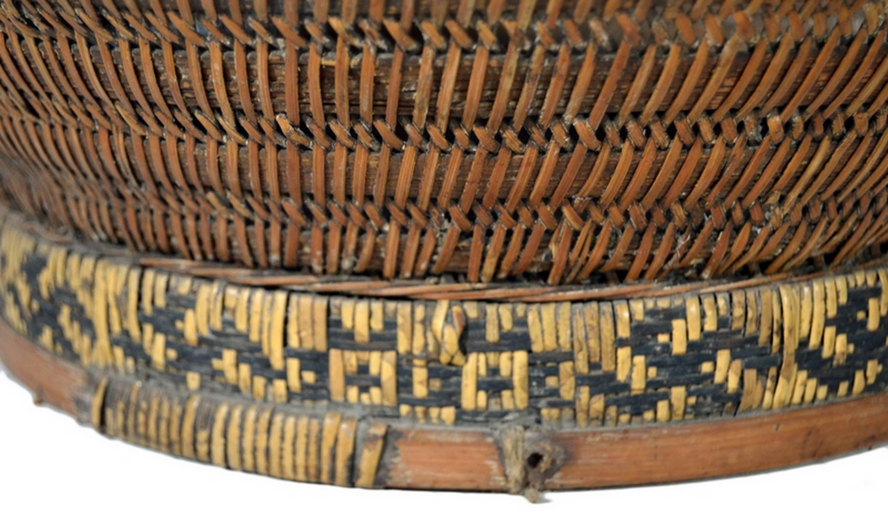 A 19th century Chinese grain basket handwoven of cane and bamboo. In 19th century China baskets such as these were used to store or transport grain. It features a base of cane, woven with an intricate star-shaped pattern on a bamboo framework. The