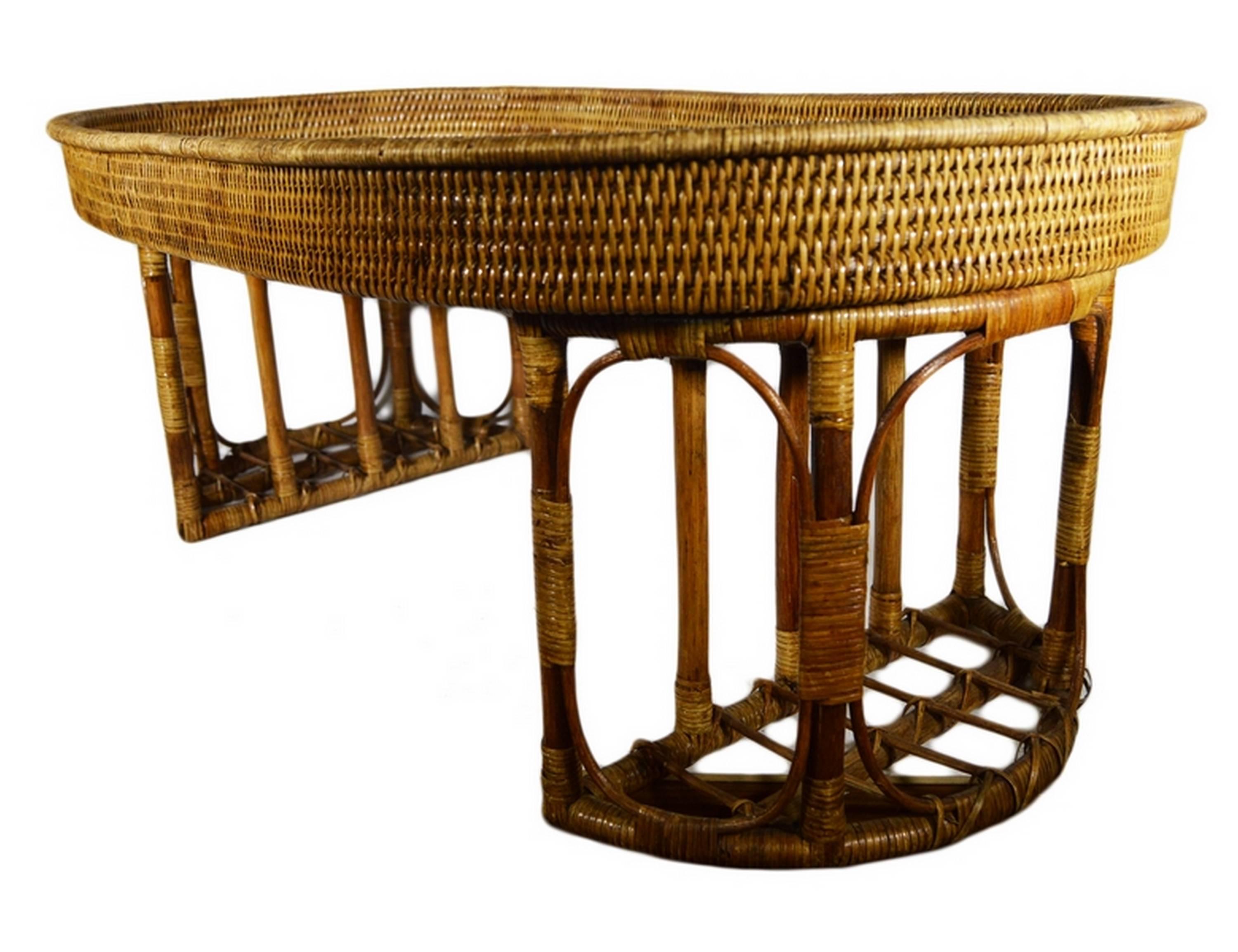 A 20th century coffee serving table handwoven with rattan in Burma. This table adopts an oval shape resting on two half-moon legs. These legs are made with thick rattan rods organized as an openwork ensemble. The top is handwoven with fine rattan