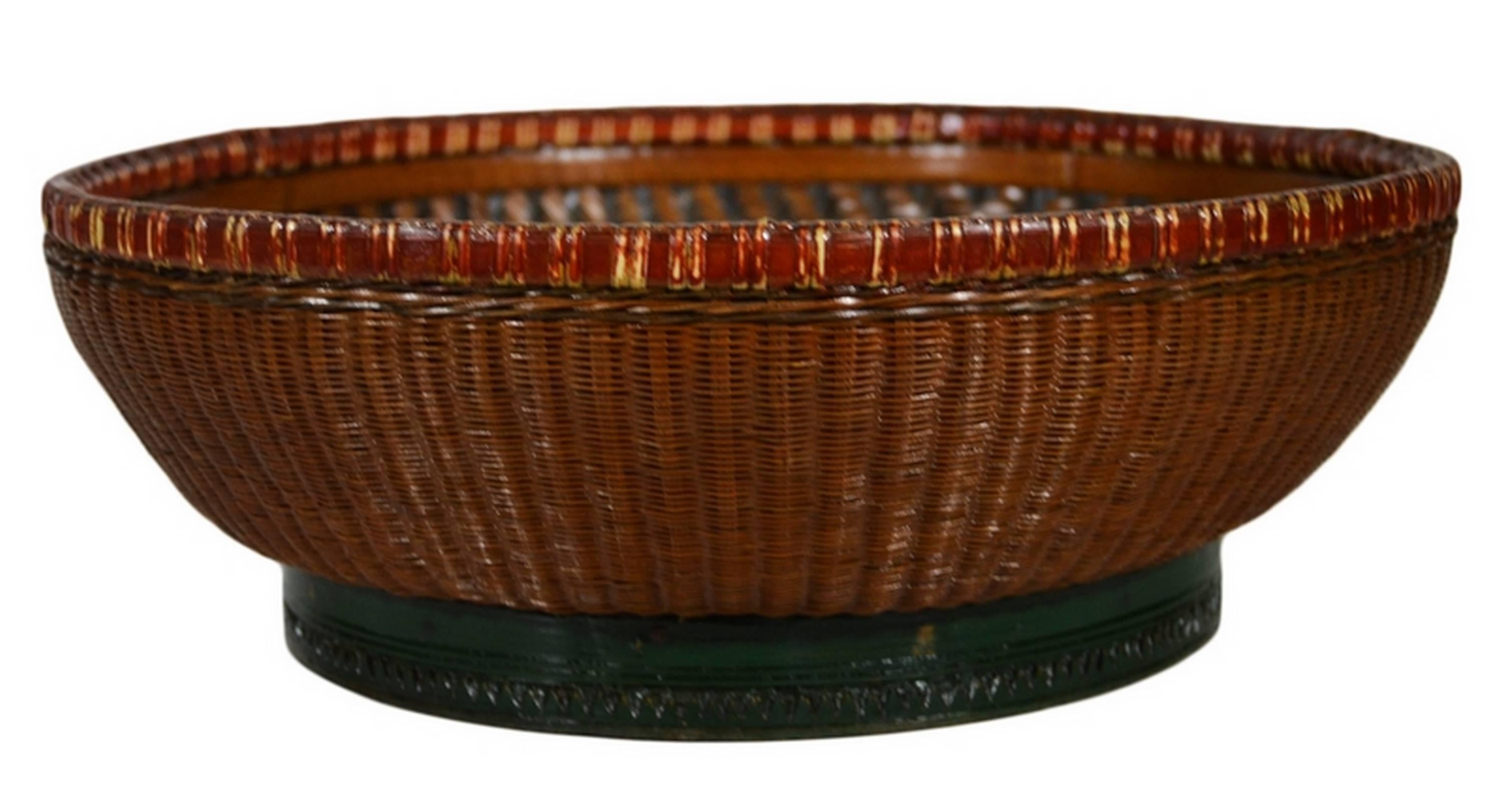 A 19th century Chinese grain basket hand woven of bamboo and rattan. Baskets such as these were often used to store grain in 19th century China. It features a bamboo base and rim with a hand woven, interlaced rattan on the outside. Inside, the black