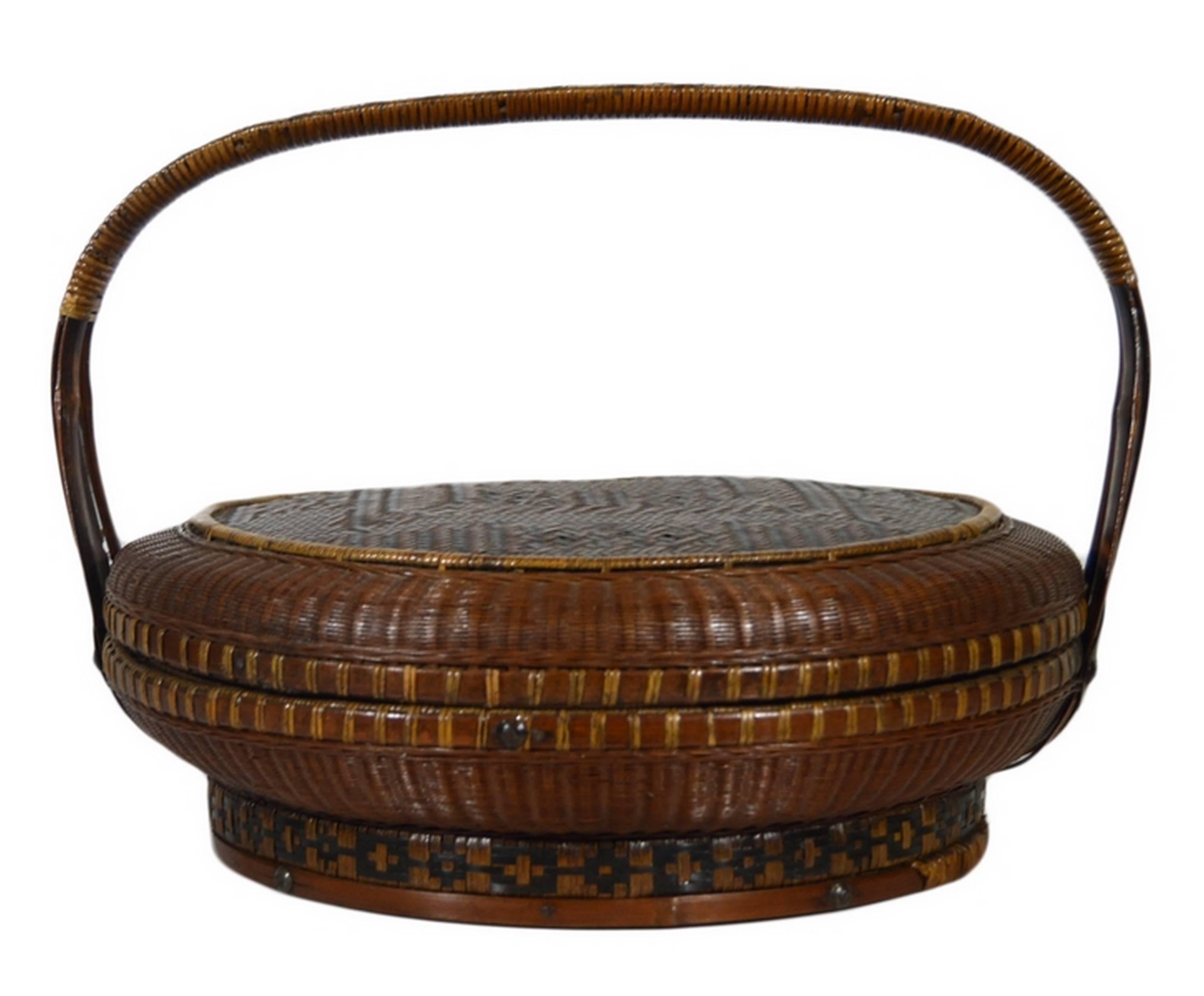 A Chinese 19th century brown basket handwoven with rattan and bamboo. This circular basket features a squat handle showcasing Chinese calligraphy on its bamboo parts. The middle part is covered with a two colored rattan. The base of this basket